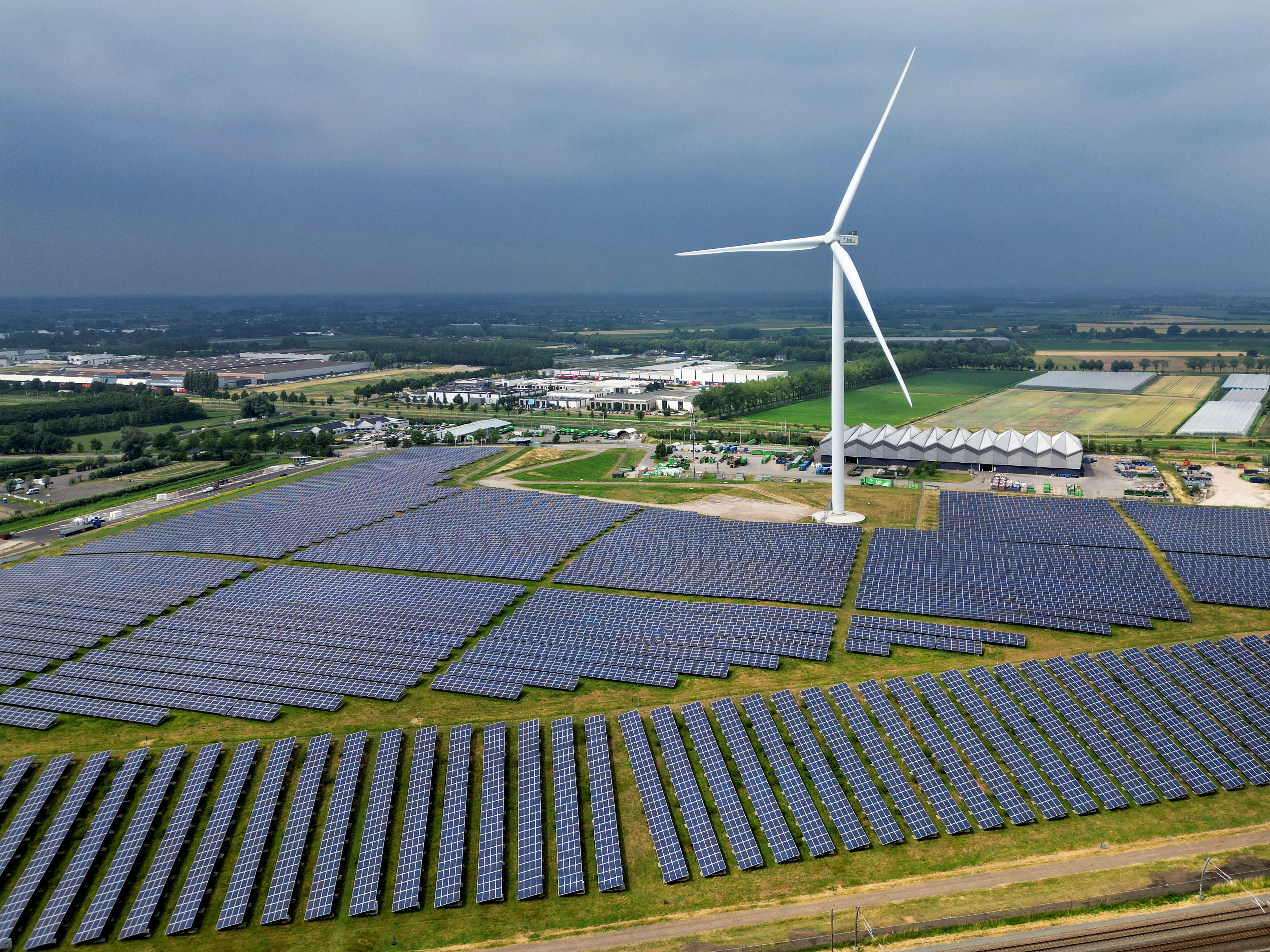 A solar panel park and a wind turbine are seen along the highway in Geldermalsen, Netherlands