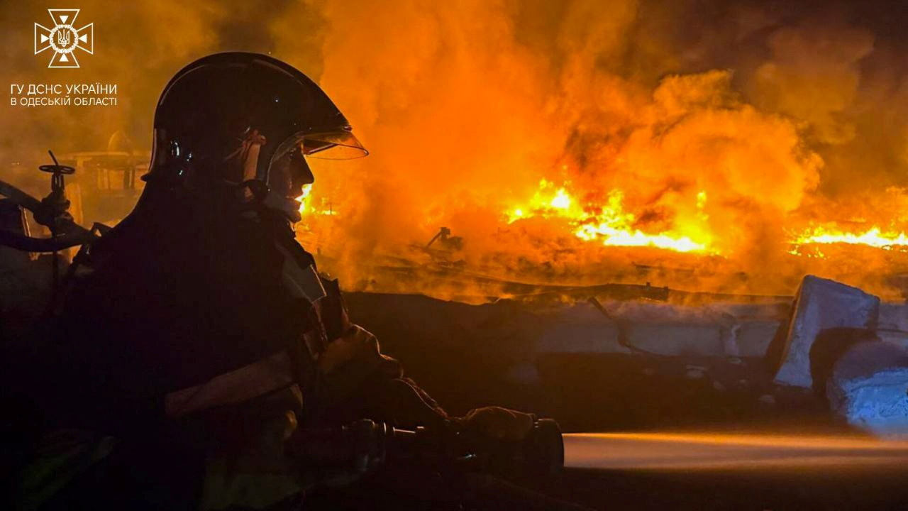 A firefighter working at scene of a drone attack in Odesa region He is silhouetted against the orange flames and smoke