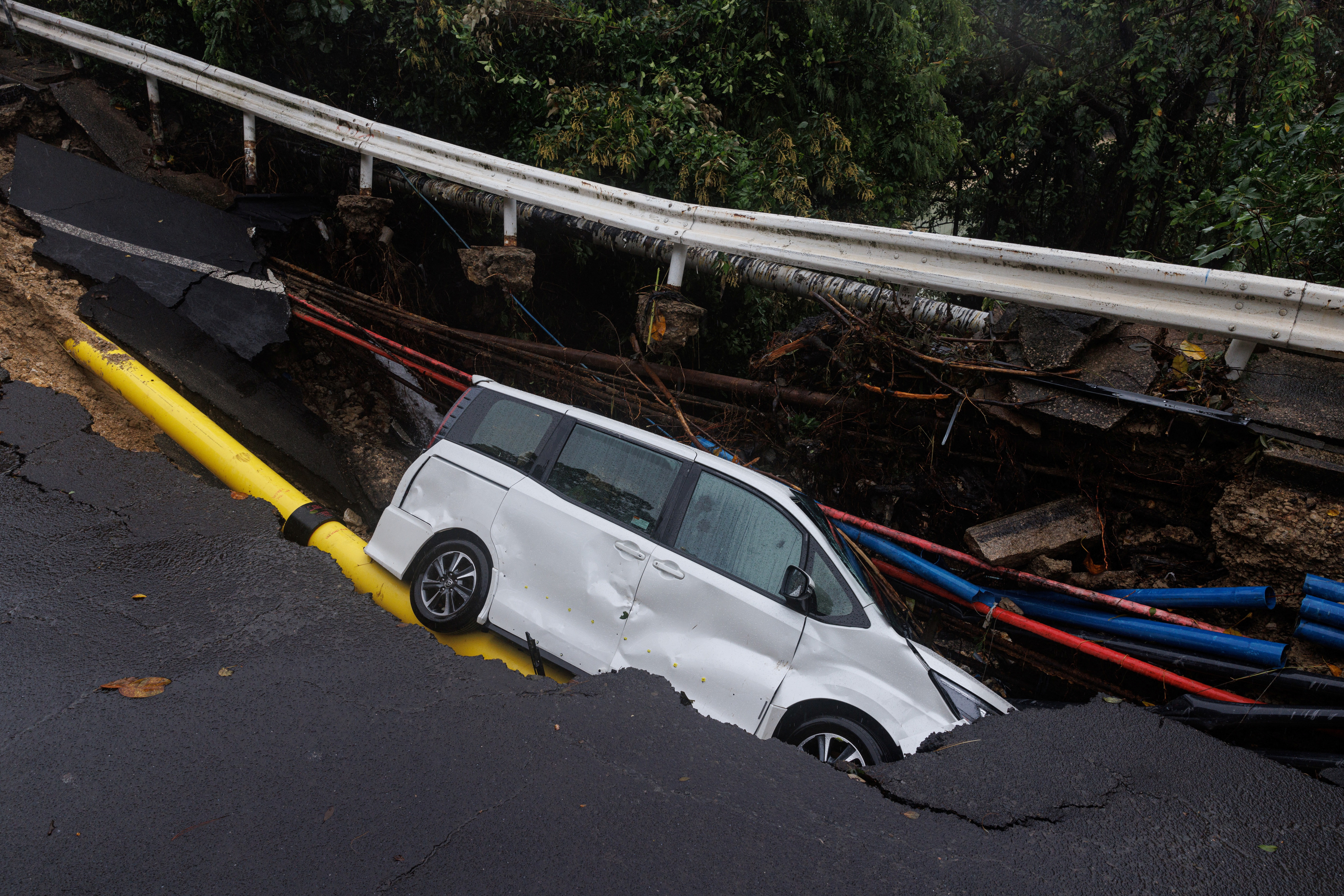 A vehicle is seen at a collapsed road section after flood and heavy rains, in Hong Kong