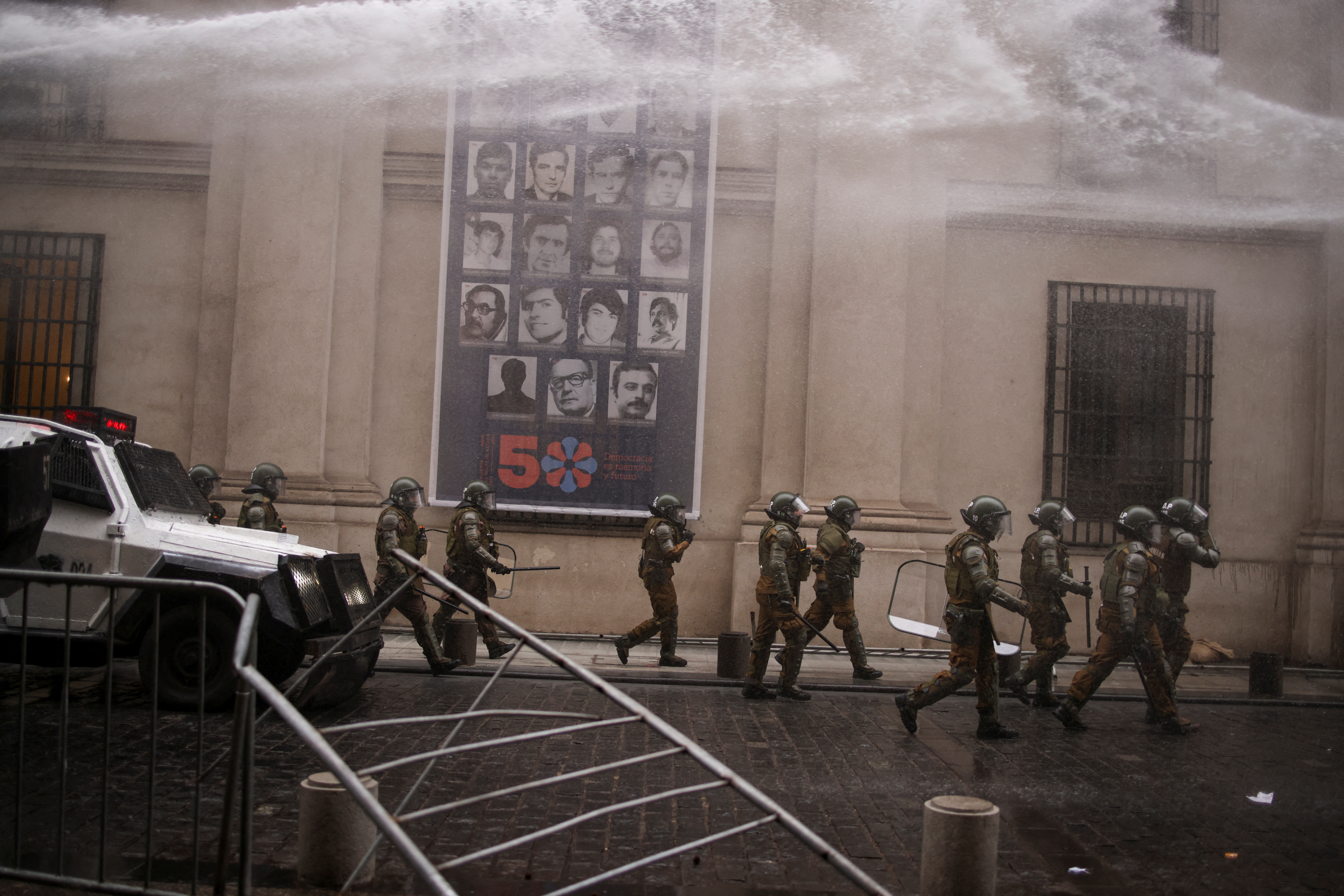 Riot police chase protesters during clashes at a rally-march ahead of the 50th anniversary of the 1973 Chilean military coup