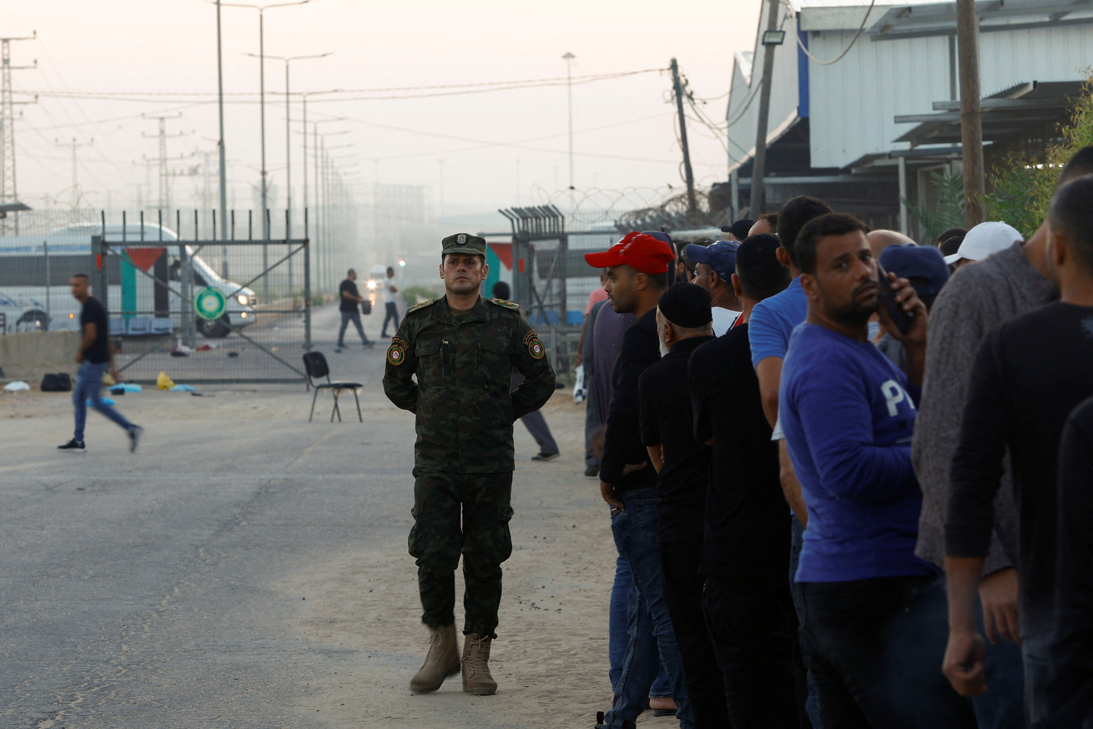 A Palestinian police officer watches a line of Palestinian workers, as they enter the reopened Erez crossing to Israel, after Israeli ends a ban on workers from Gaza,