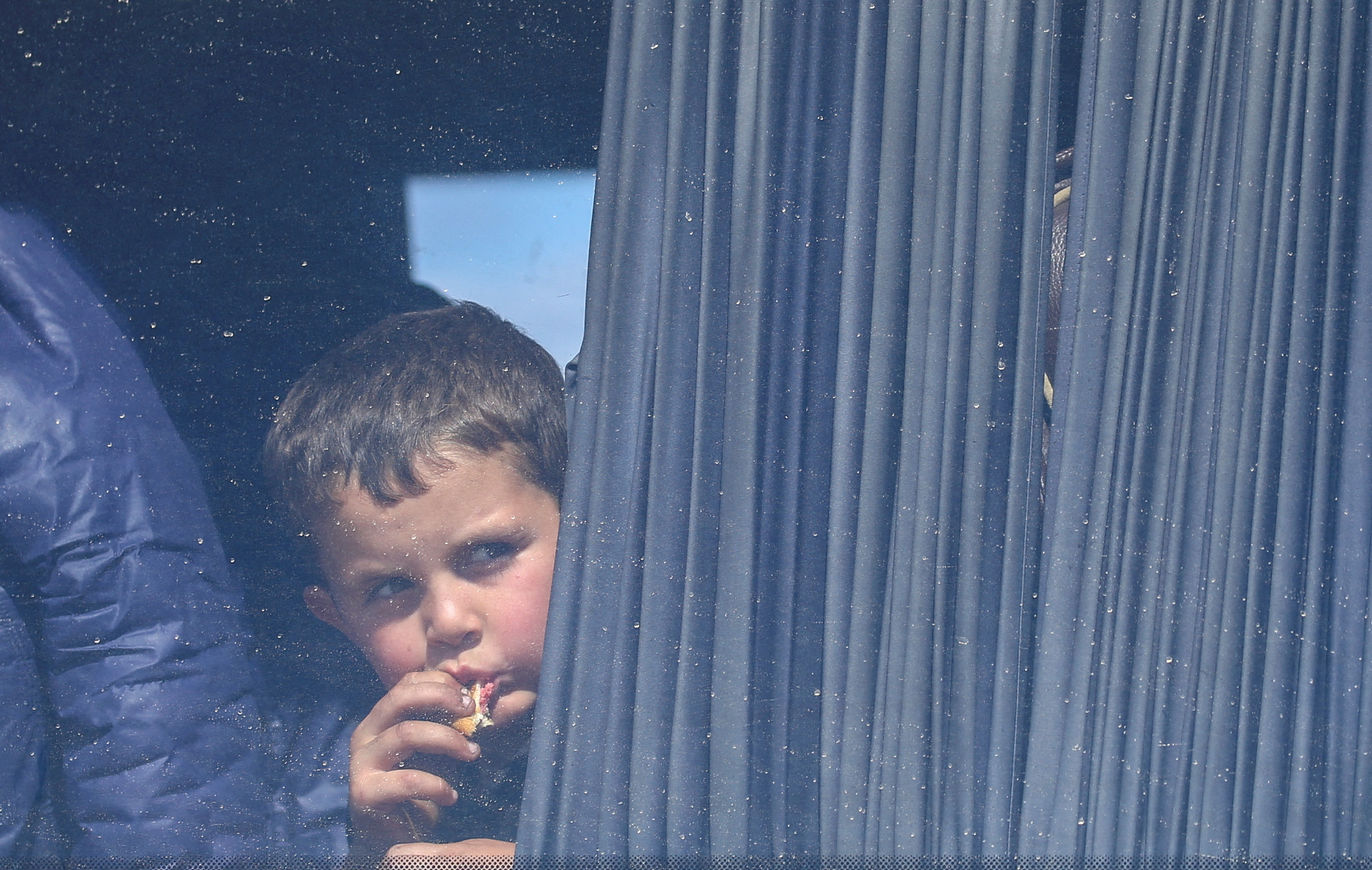 boy looks through a window of a bus used by refugees fleeing Nagorno-Karabakh region upon their arrival in the border village of Kornidzor, Armenia
