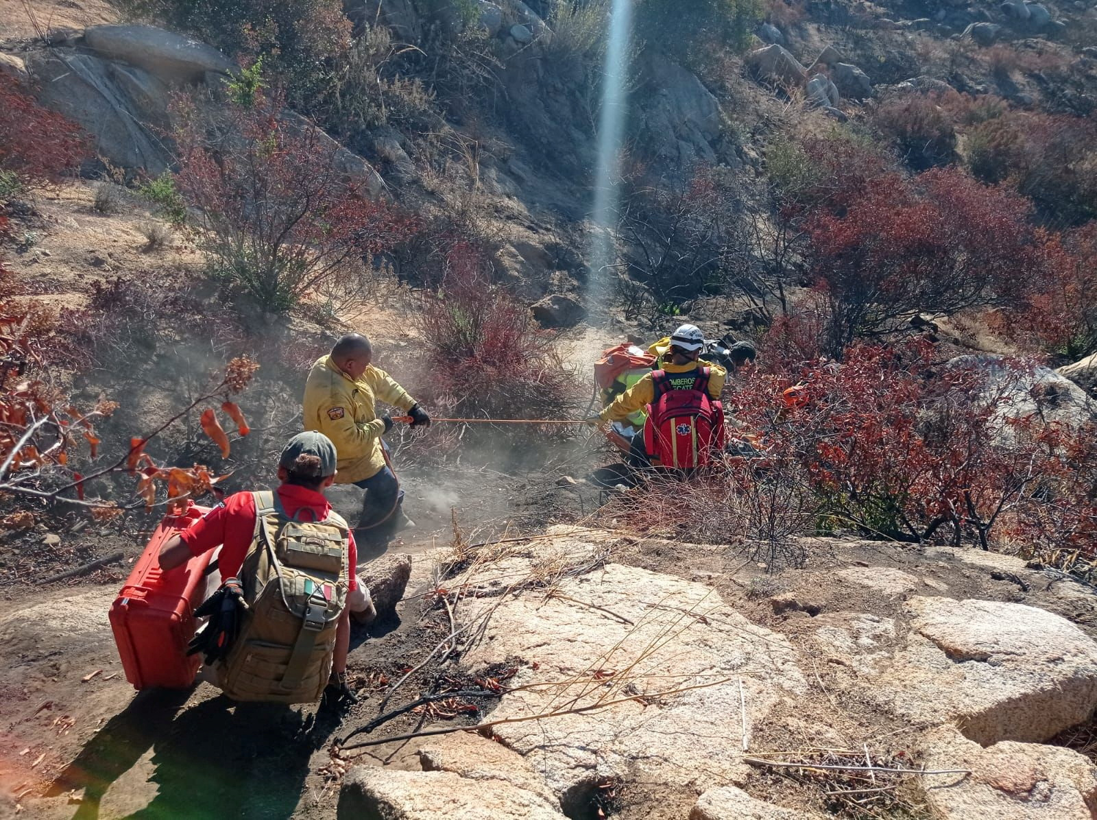 Members of the Grupo Beta group navigate a steep, arid hillside to reach an injured party.