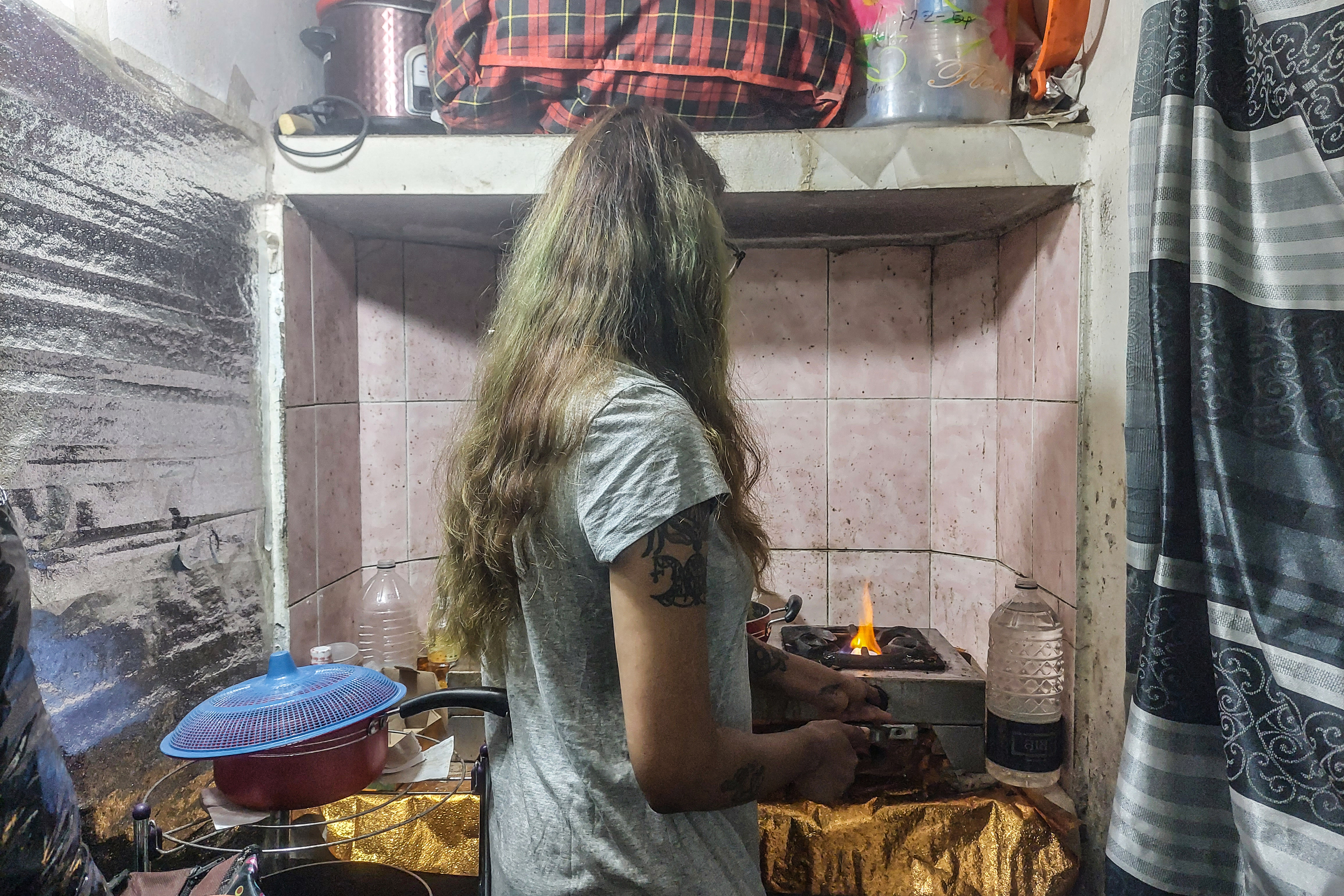 A photo of a woman cooking on a small stove.
