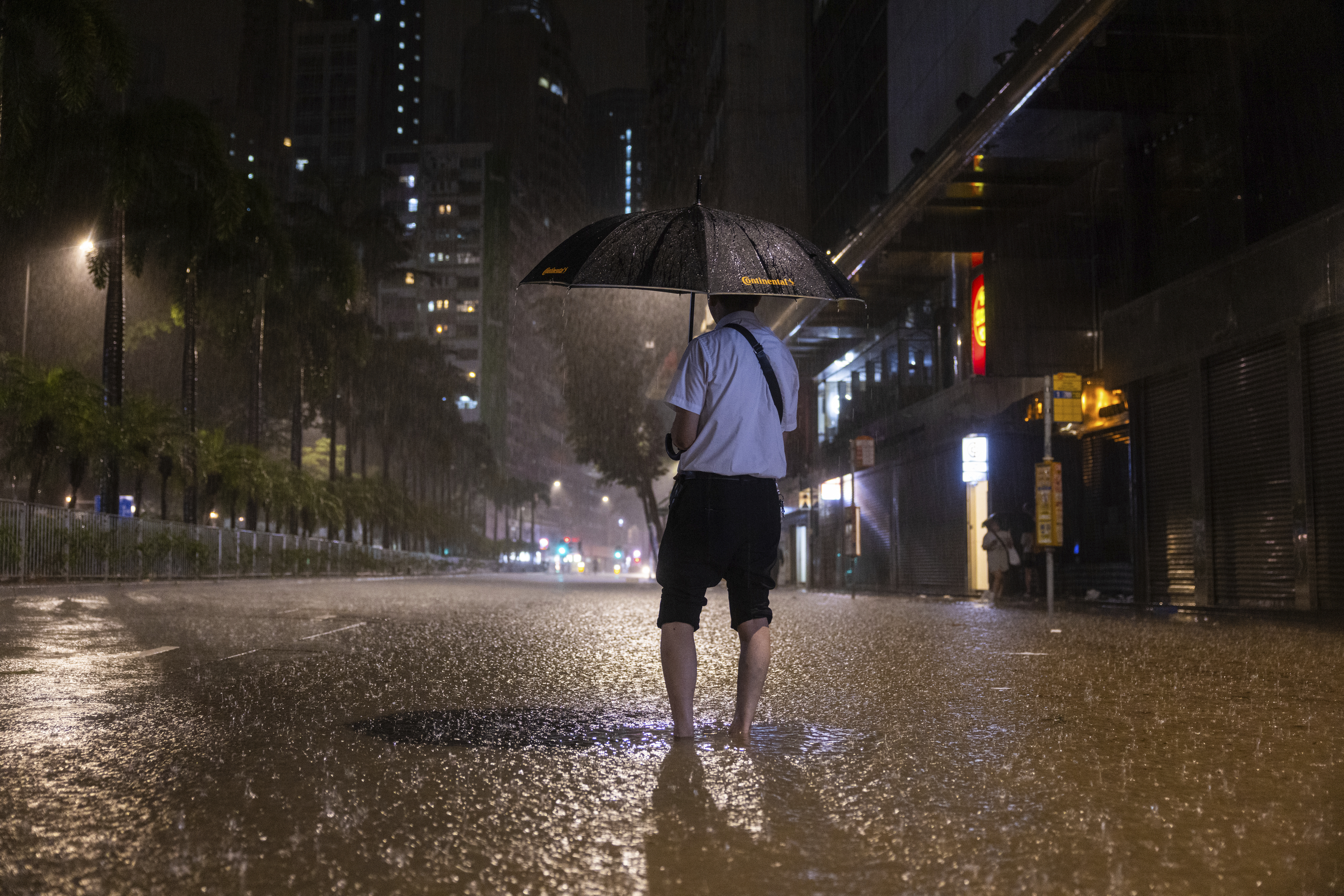 A pedestrian waits for a bus on a flooded street following heavy rainstorms in Hong Kong