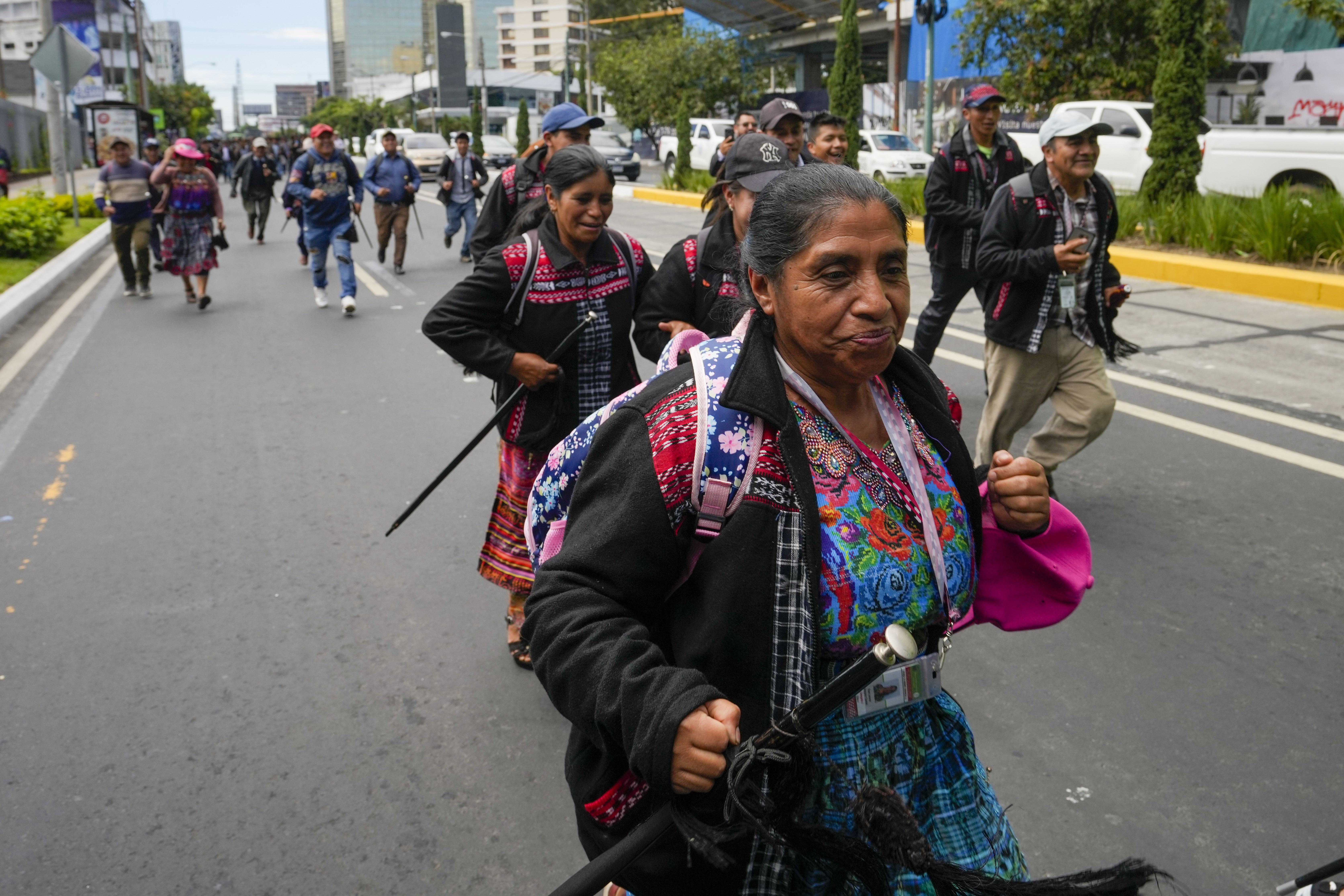 An Indigenous woman in colorful regalia marches down the streets of Guatemala City.