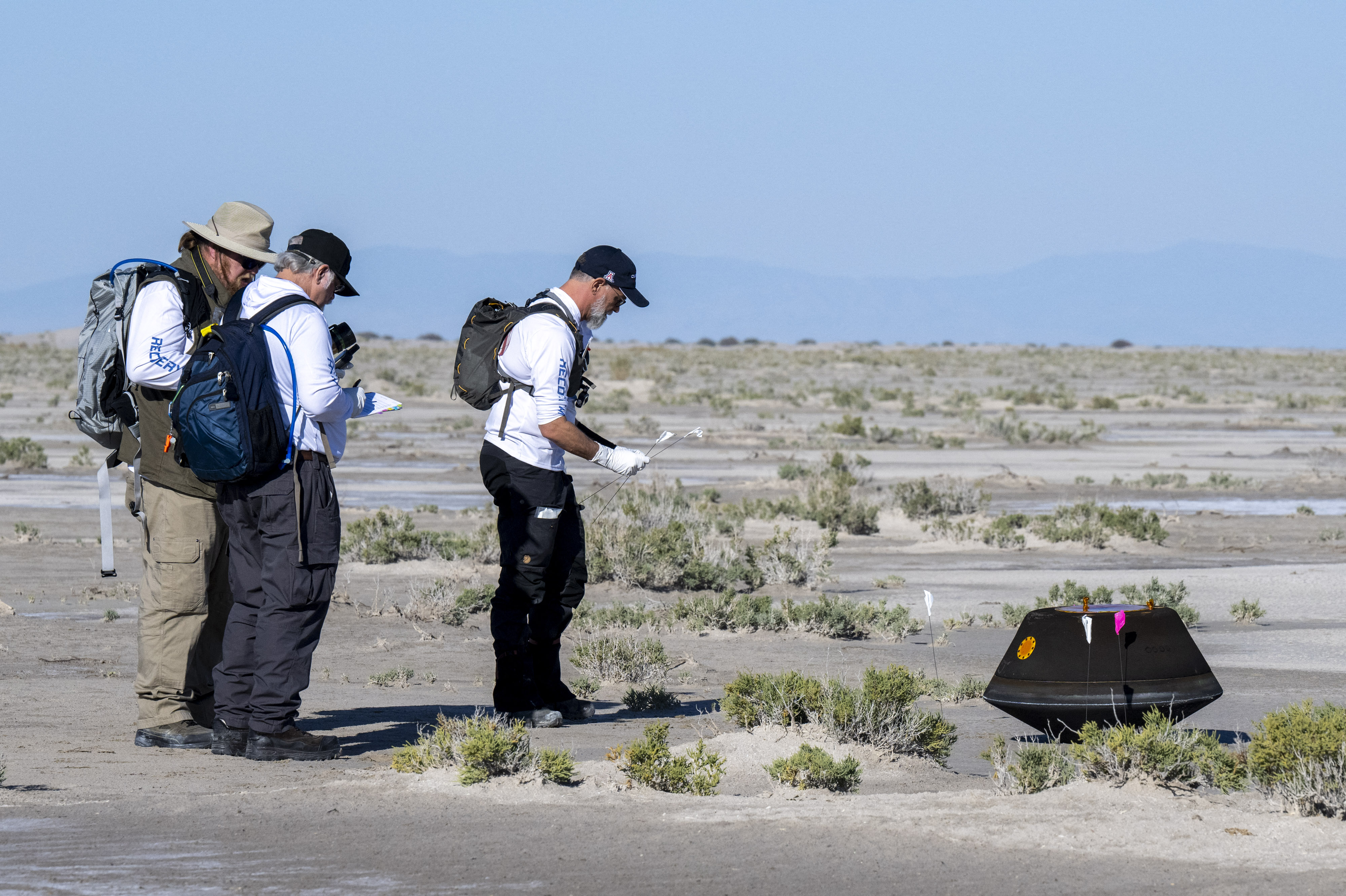 DUGWAY, UTAH - SEPTEMBER 24: In this handout provided by NASA, from left to right, NASA Astromaterials Curator Francis McCubbin, NASA Sample Return Capsule Science Lead Scott Sandford, and University of Arizona OSIRIS-REx Principal Investigator Dante Lauretta collect science data shortly after the sample return capsule from NASA's OSIRIS-REx mission landed at the Department of Defense's Utah Test and Training Range, on September 24, 2023 at the Department of Defense's Utah Test and Training Range in Dugway, Utah. The sample was collected from the asteroid Bennu in October 2020 by NASA's OSIRIS-REx spacecraft. Keegan Barber/NASA via Getty Images/AFP (Photo by NASA / GETTY IMAGES NORTH AMERICA / Getty Images via AFP)