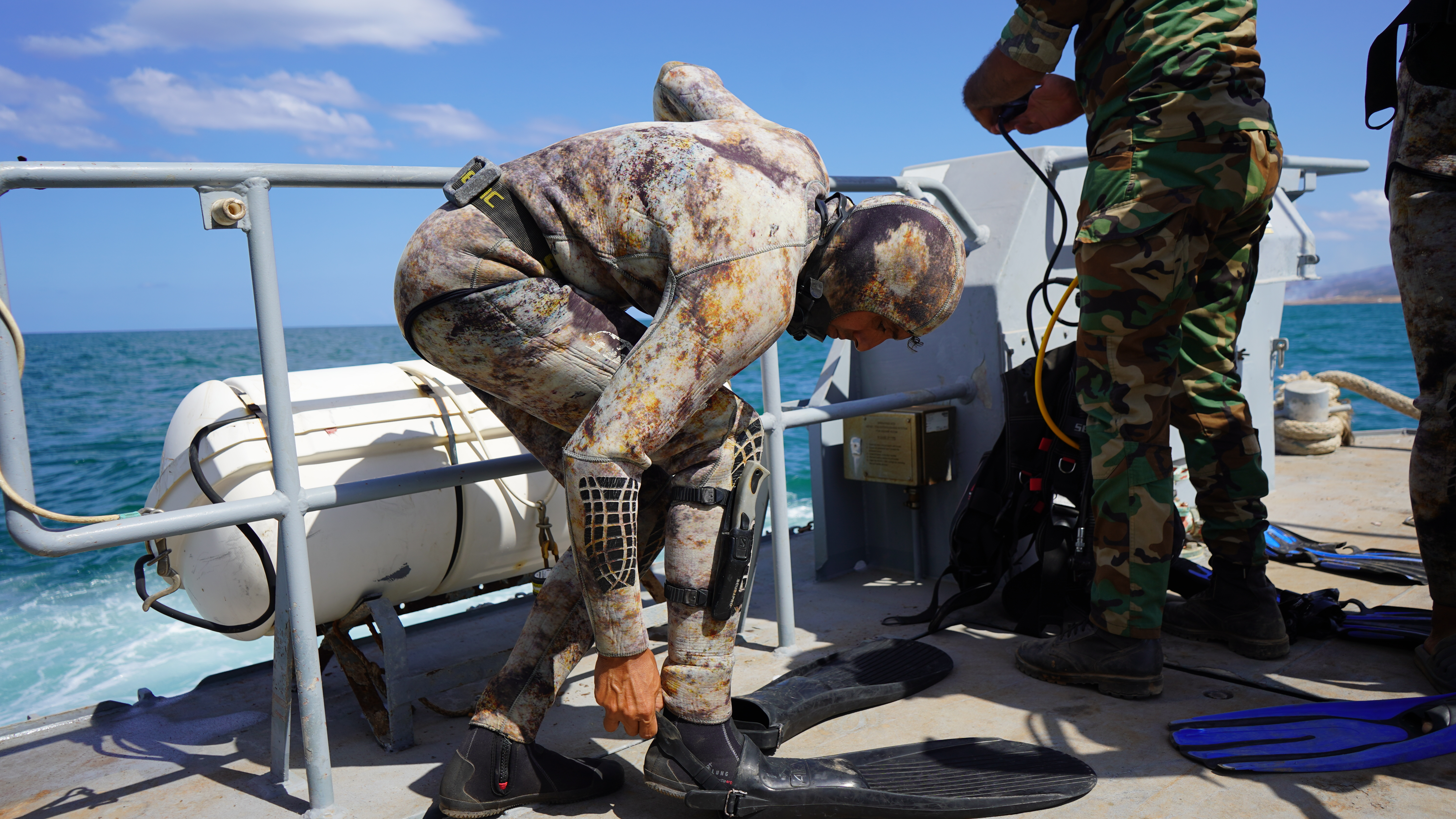 The divers help each other prepare for the dive 
