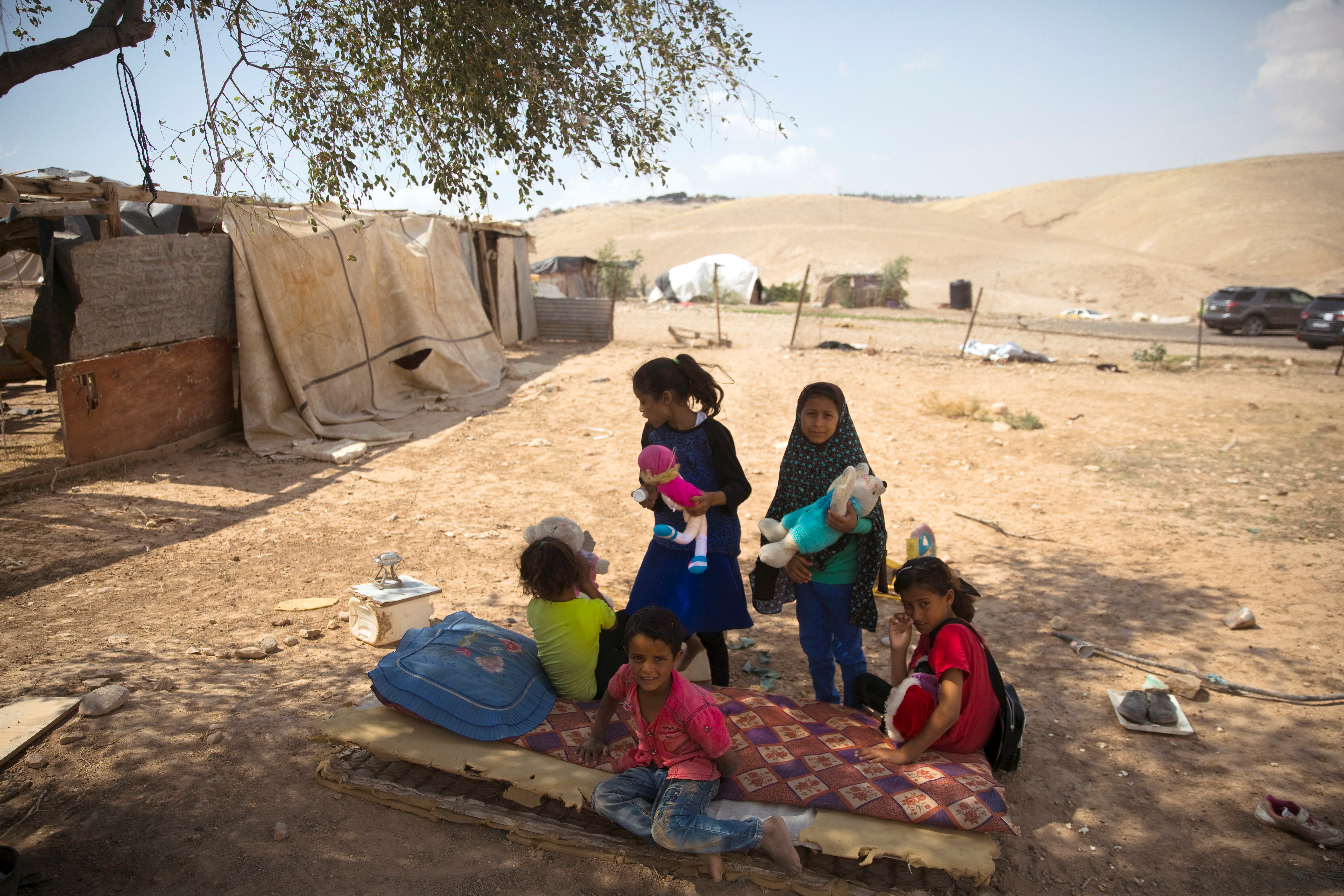 Kids play under a tree at the Bedouin encampment of al-Khan al-Ahmar near the West Bank city of Jericho May 30, 2018.