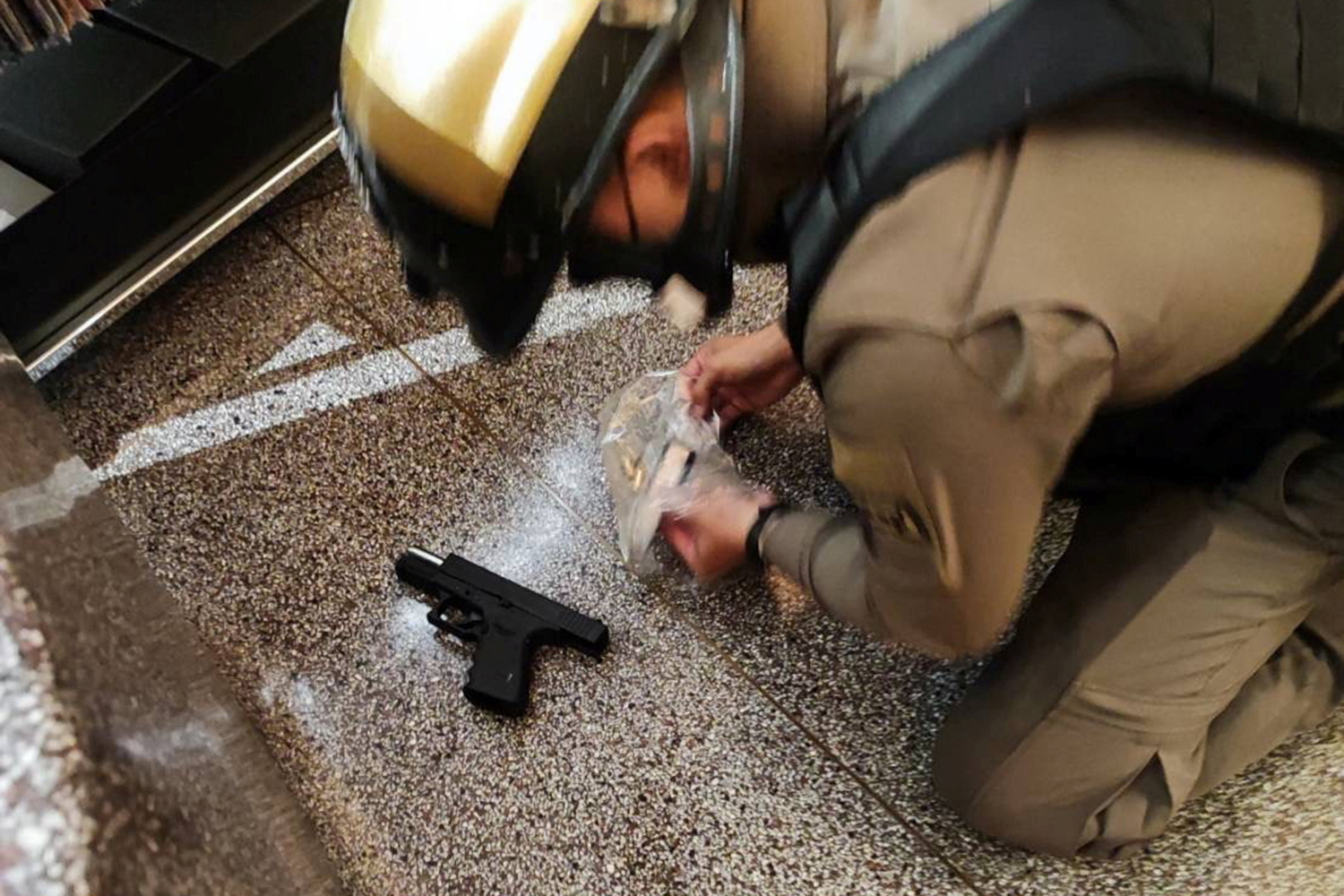 A police officer collects a gun following shots fired at the luxury Siam Paragon shopping mall, in Bangkok