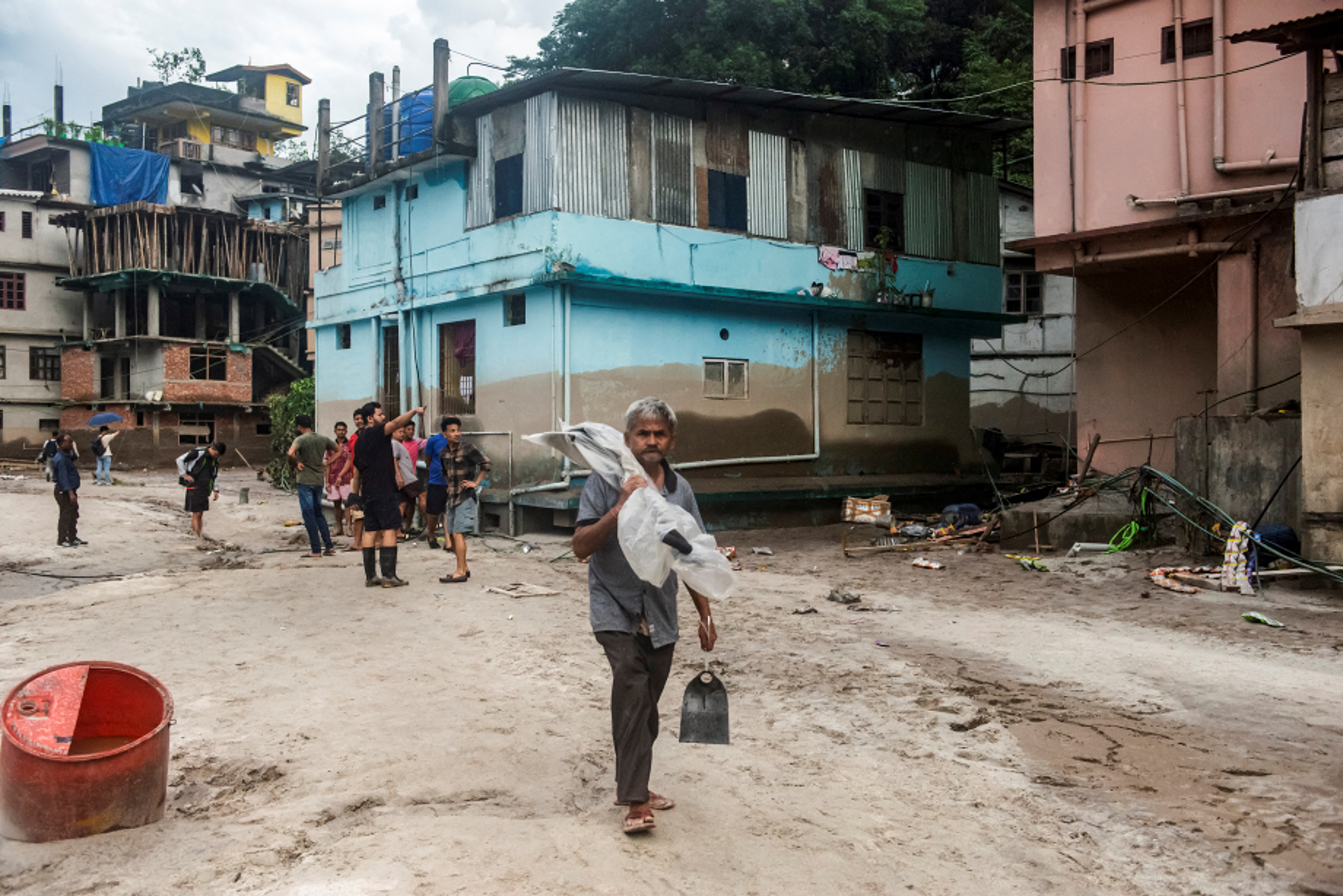 A man carrying shovels walks along an area affected by the flood near the bank of Teesta River at Singtam