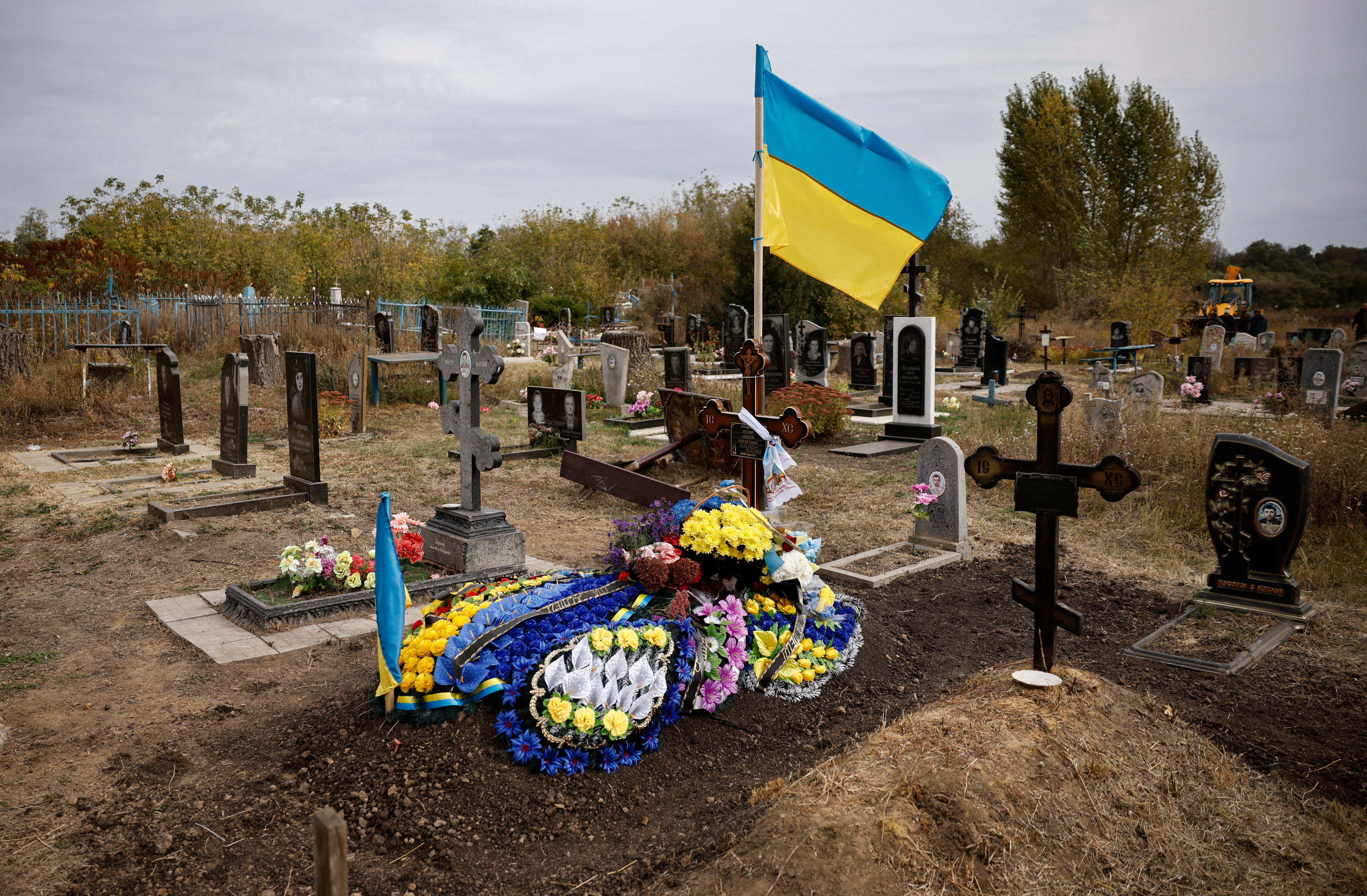 Wreaths are placed over the grave of Andriy Kozyr, a Ukrainian soldier whose wake was hit by a Russian military strike