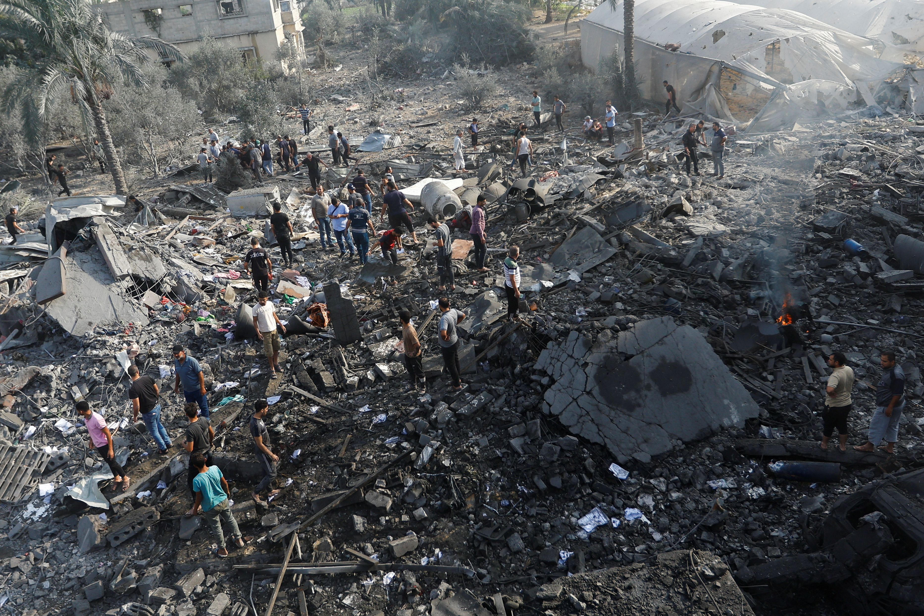 Palestinians gather on rubble in the aftermath of Israeli strikes, in Khan Younis