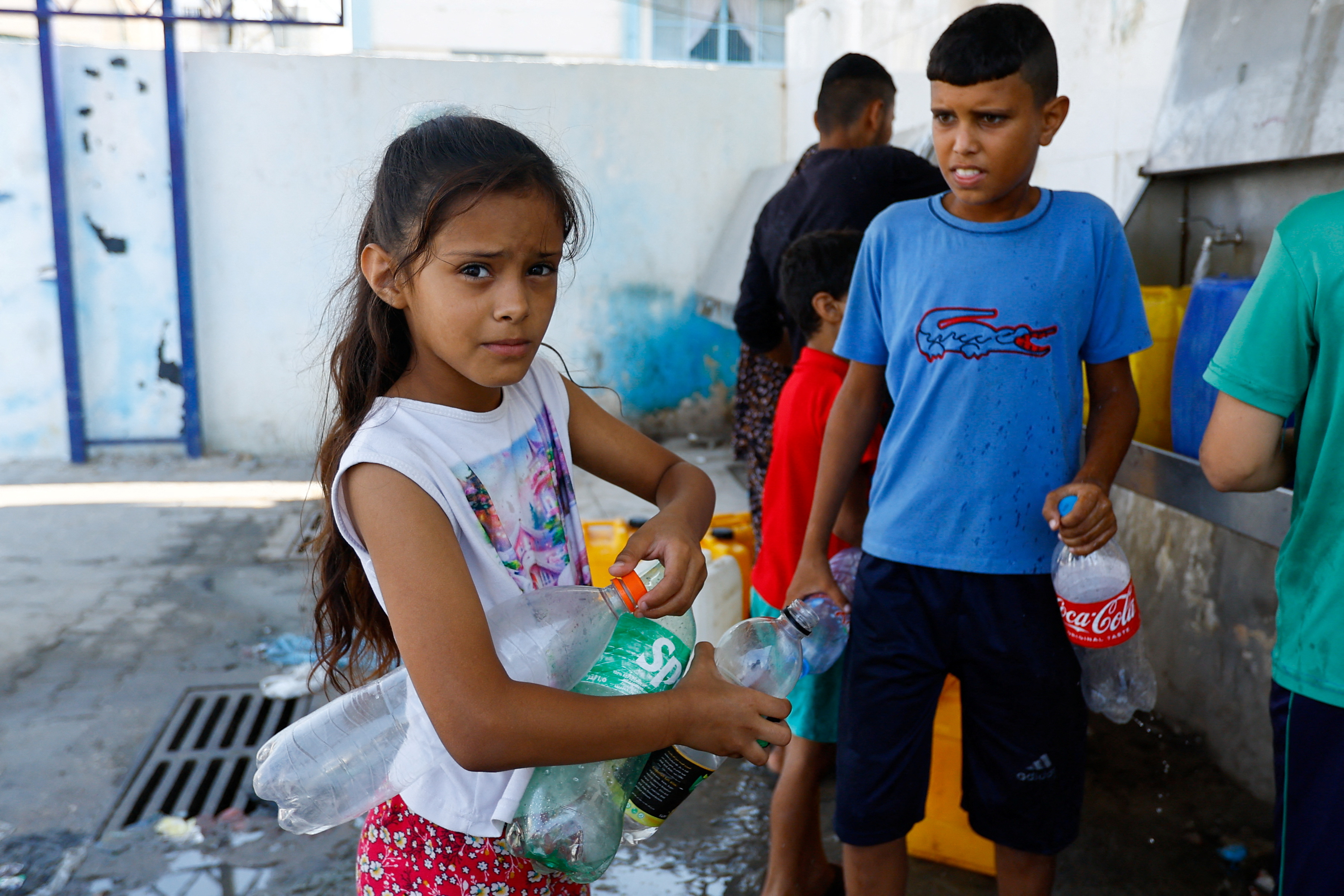Palestinian children gather to fill bottles with water from public taps amid the conflict with Israel in Khan Youni