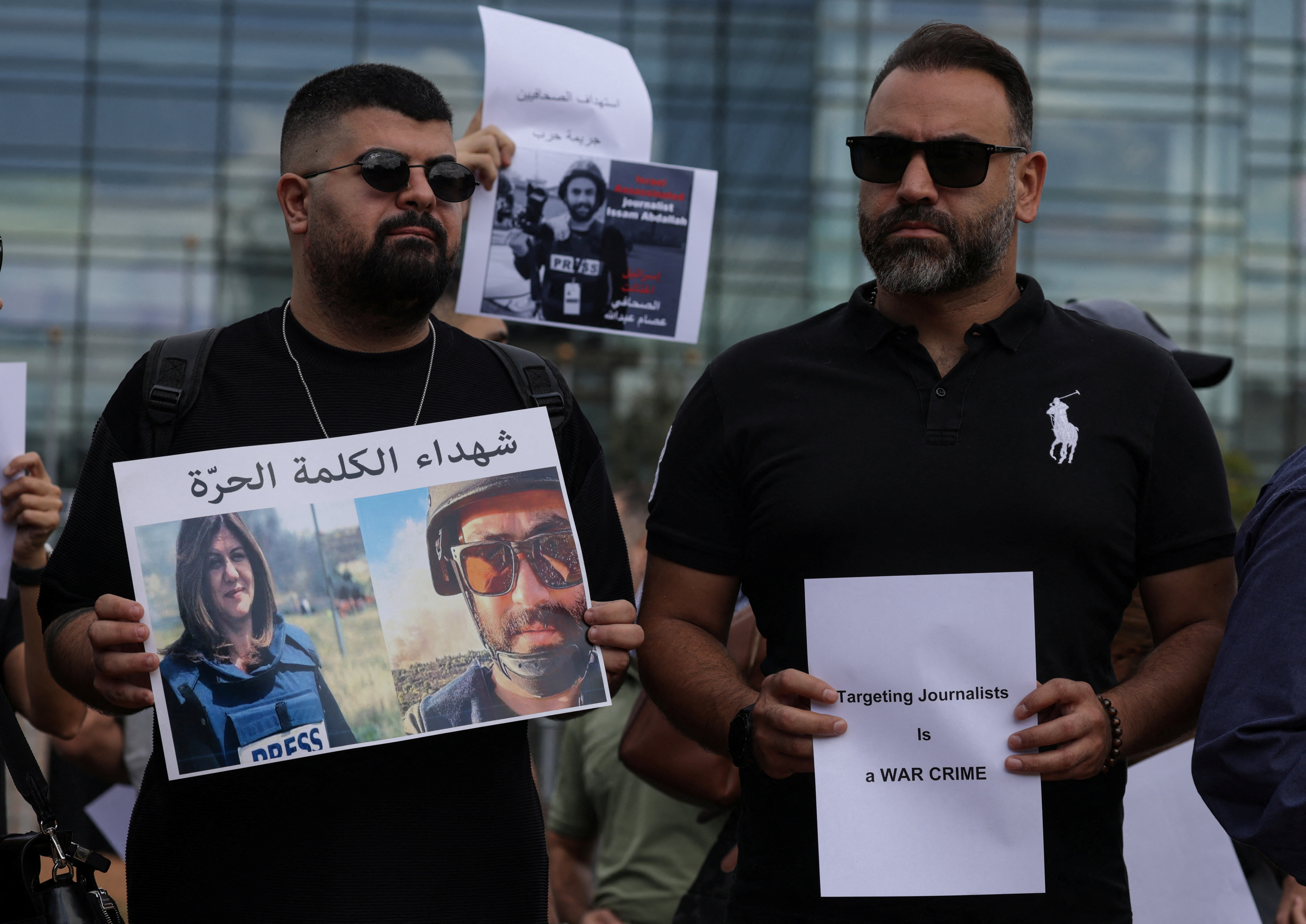 Lebanese journalists protest on the street, holding side by side photos of Issam Abdallah and Shireen Abu Akleh