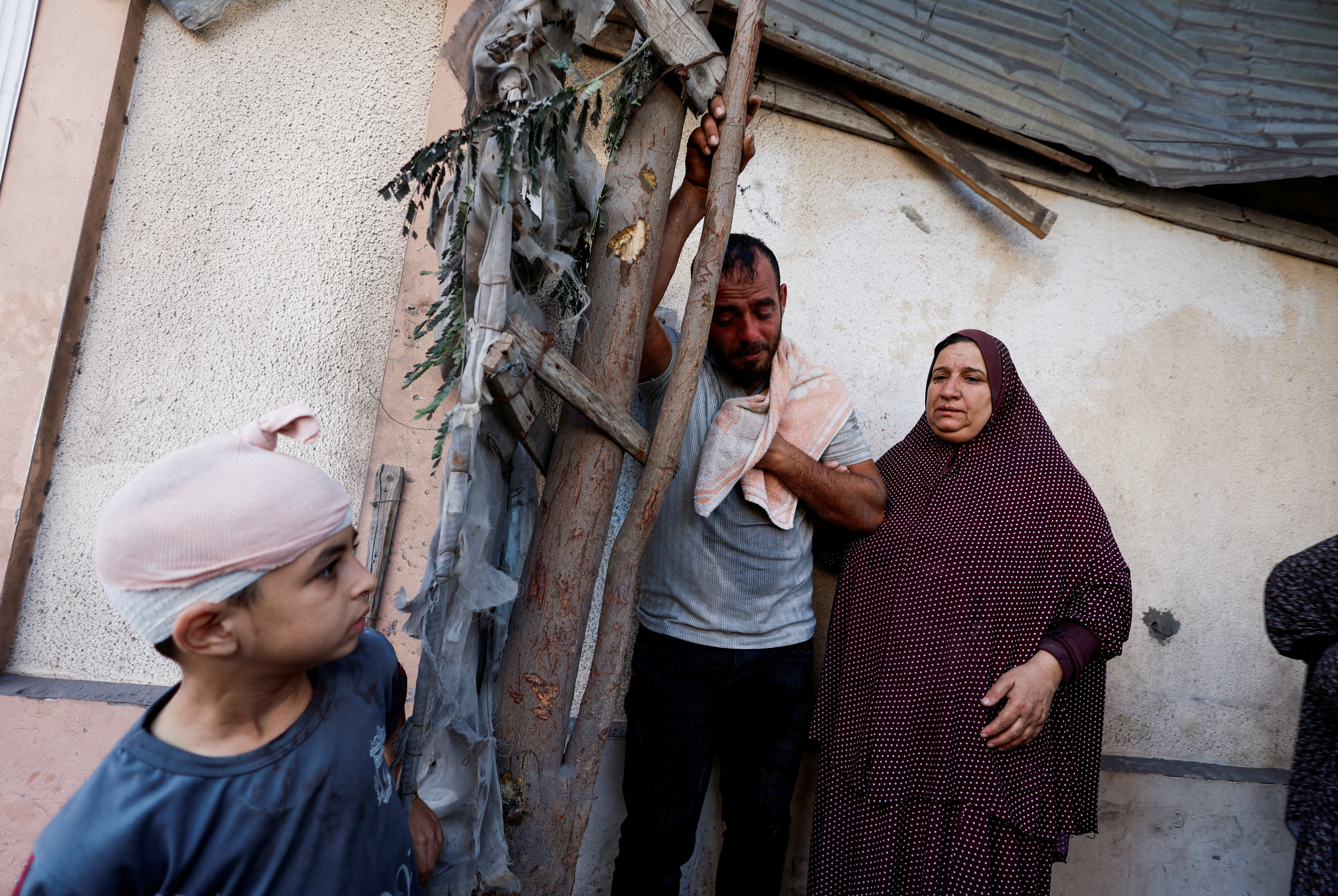 Palestinians react as people search for casualties under the rubble of a building destroyed by Israeli strikes in Khan Younis