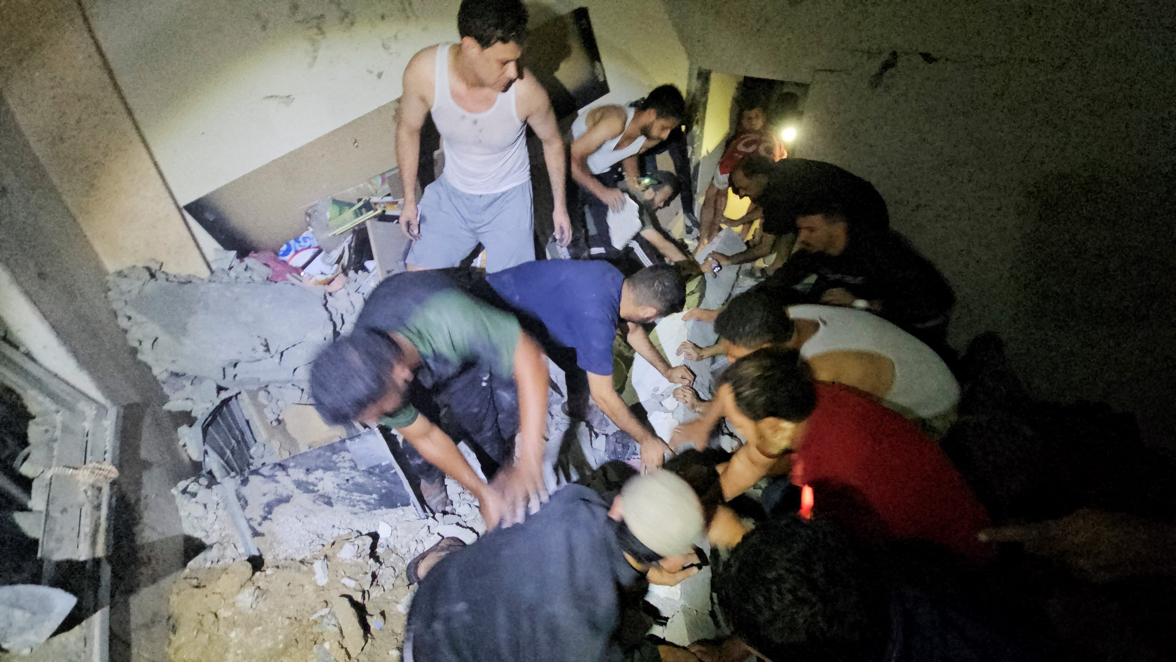 Palestinians work to rescue a boy trapped in the rubble following an Israeli strike on a house in Jabalia in the northern Gaza Strip, October 19, 2023