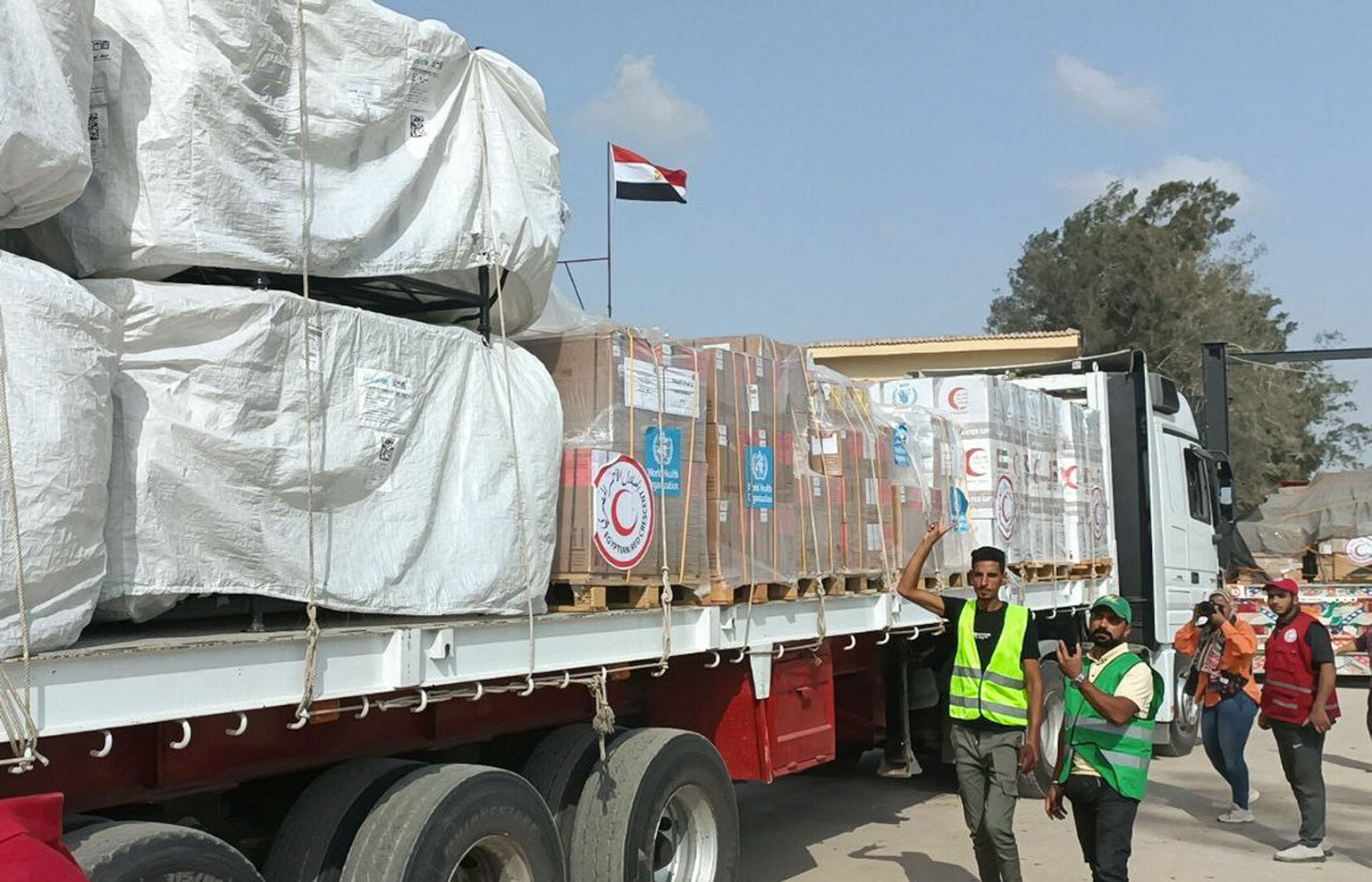 Egyptian Red Crescent members and volunteers gather next to a truck carrying humanitarian aid as it drives through the Rafah crossing from the Egyptian side.