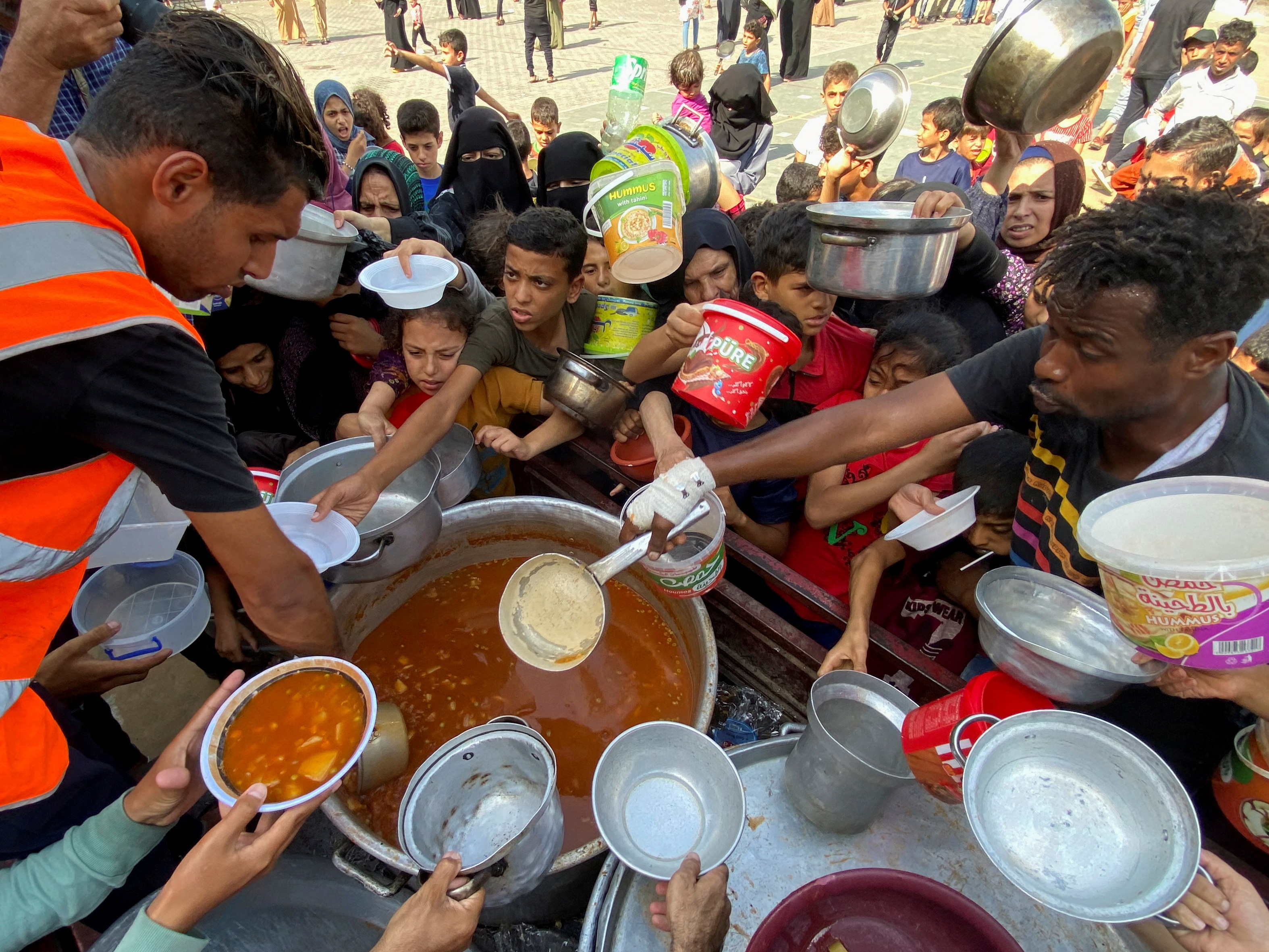 People in Gaza with bowls outstretched as they wait for food