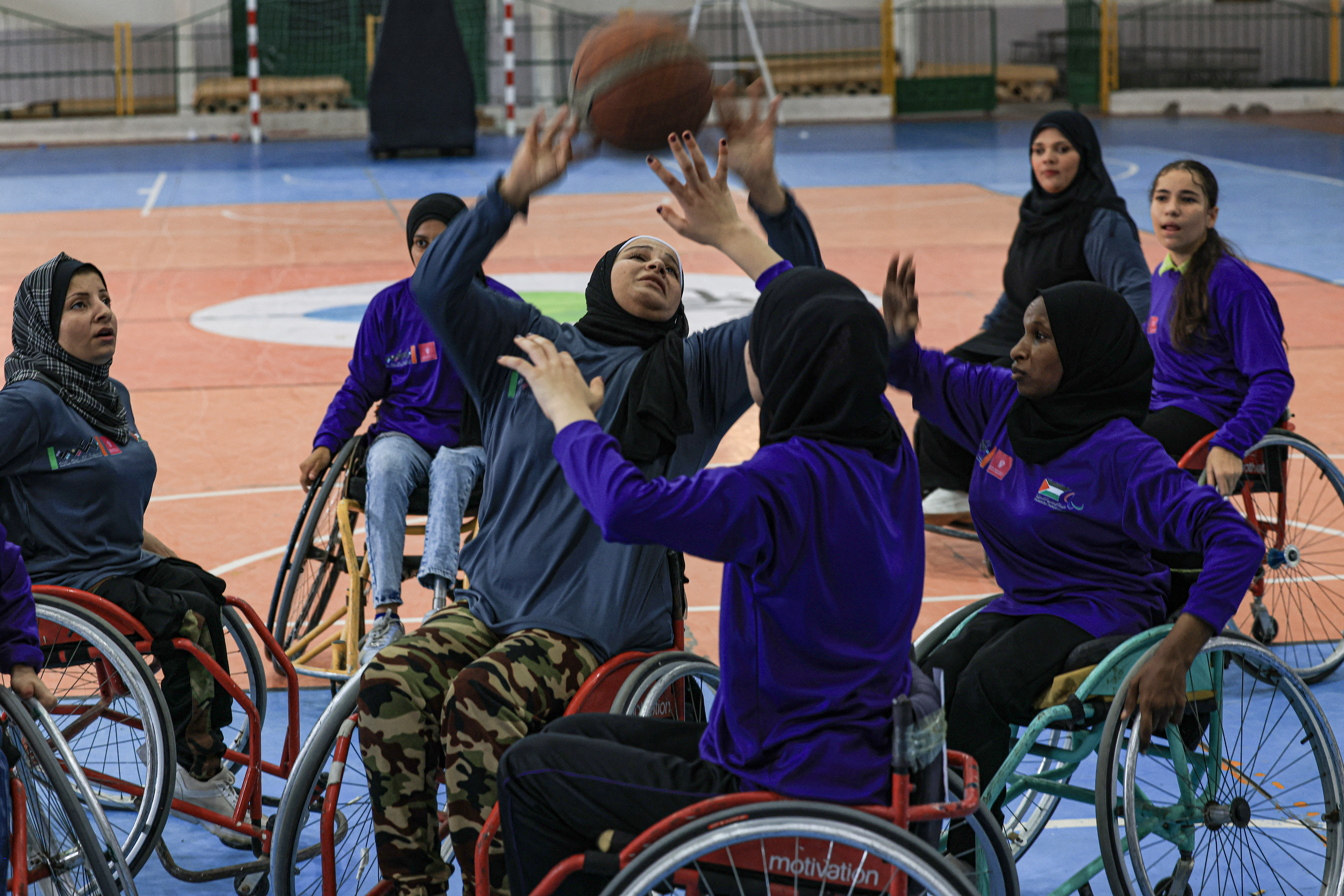 Disabled women in wheelchairs play basketball in a covered gymnasium in Gaza City