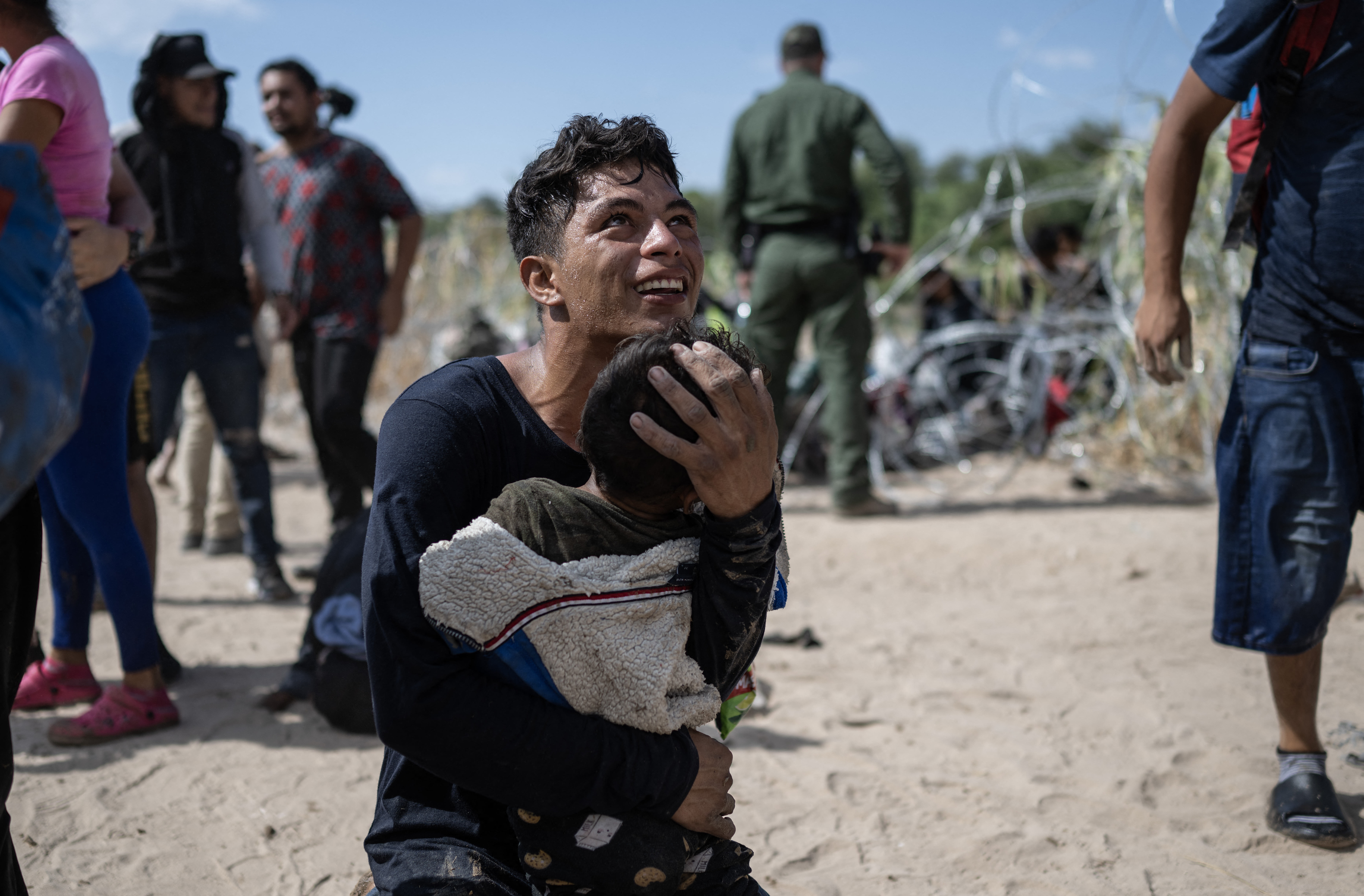 A migrant family from Venezuela reacts after breaking through a razor wire barricade into the United States,