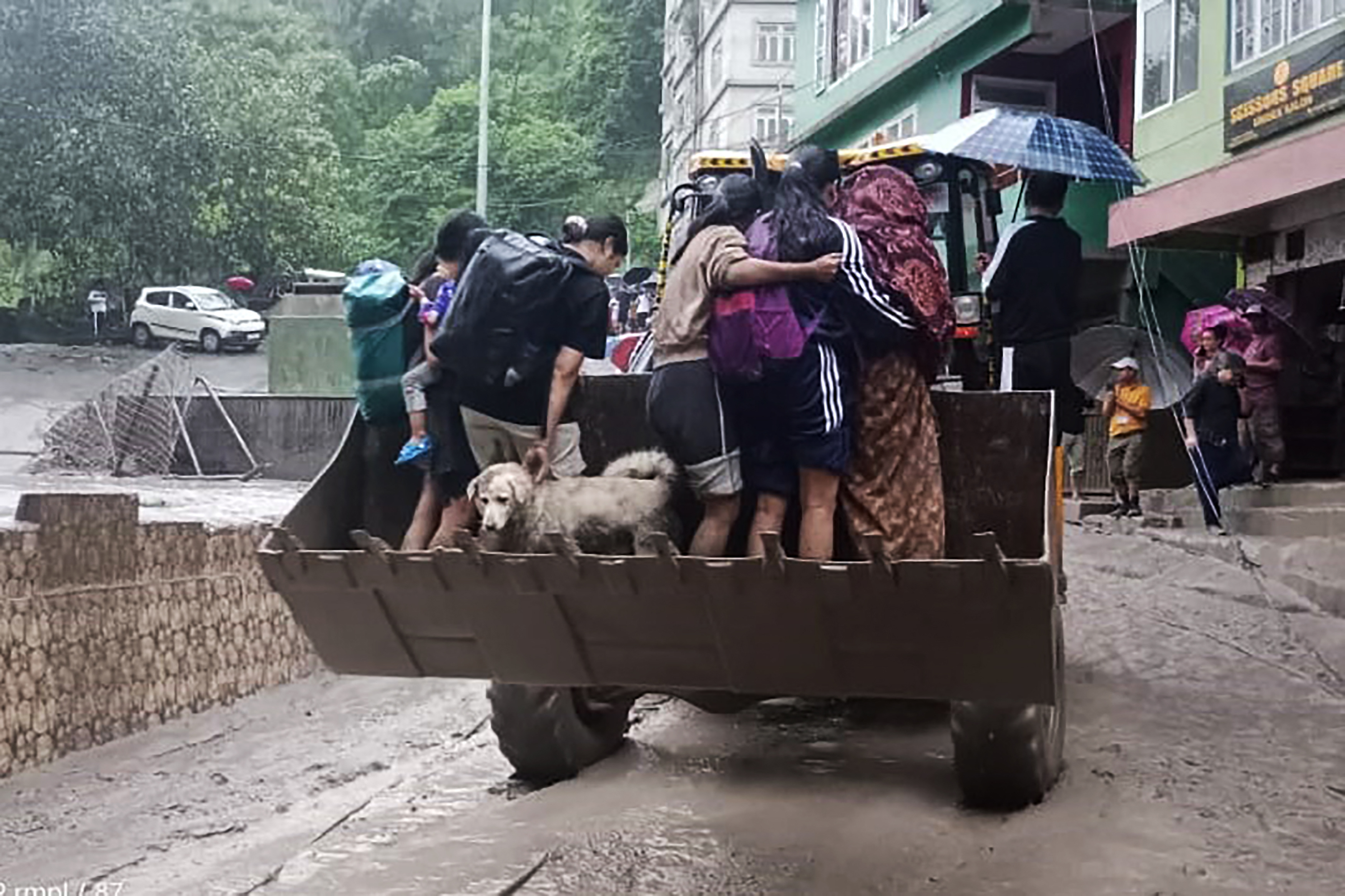 This handout photograph released by the Indian Ministry of Defence and taken on October 4, 2023, shows residents being evacuated on a backhoe loader in Muguthang, in India's Sikkim state following a flash flood caused by intense rainfall. - The Indian army said October 4 that 23 soldiers were missing after a powerful flash flood caused by intense rainfall tore through a valley in the mountainous northeast Sikkim state. (Photo by INDIAN MINISTRY OF DEFENCE / AFP) / RESTRICTED TO EDITORIAL USE - MANDATORY CREDIT "AFP PHOTO / INDIAN MINISTRY OF DEFENCE- NO MARKETING NO ADVERTISING CAMPAIGNS - DISTRIBUTED AS A SERVICE TO CLIENTS - RESTRICTED TO EDITORIAL USE - MANDATORY CREDIT "AFP PHOTO / Indian Ministry of Defence- NO MARKETING NO ADVERTISING CAMPAIGNS - DISTRIBUTED AS A SERVICE TO CLIENTS /