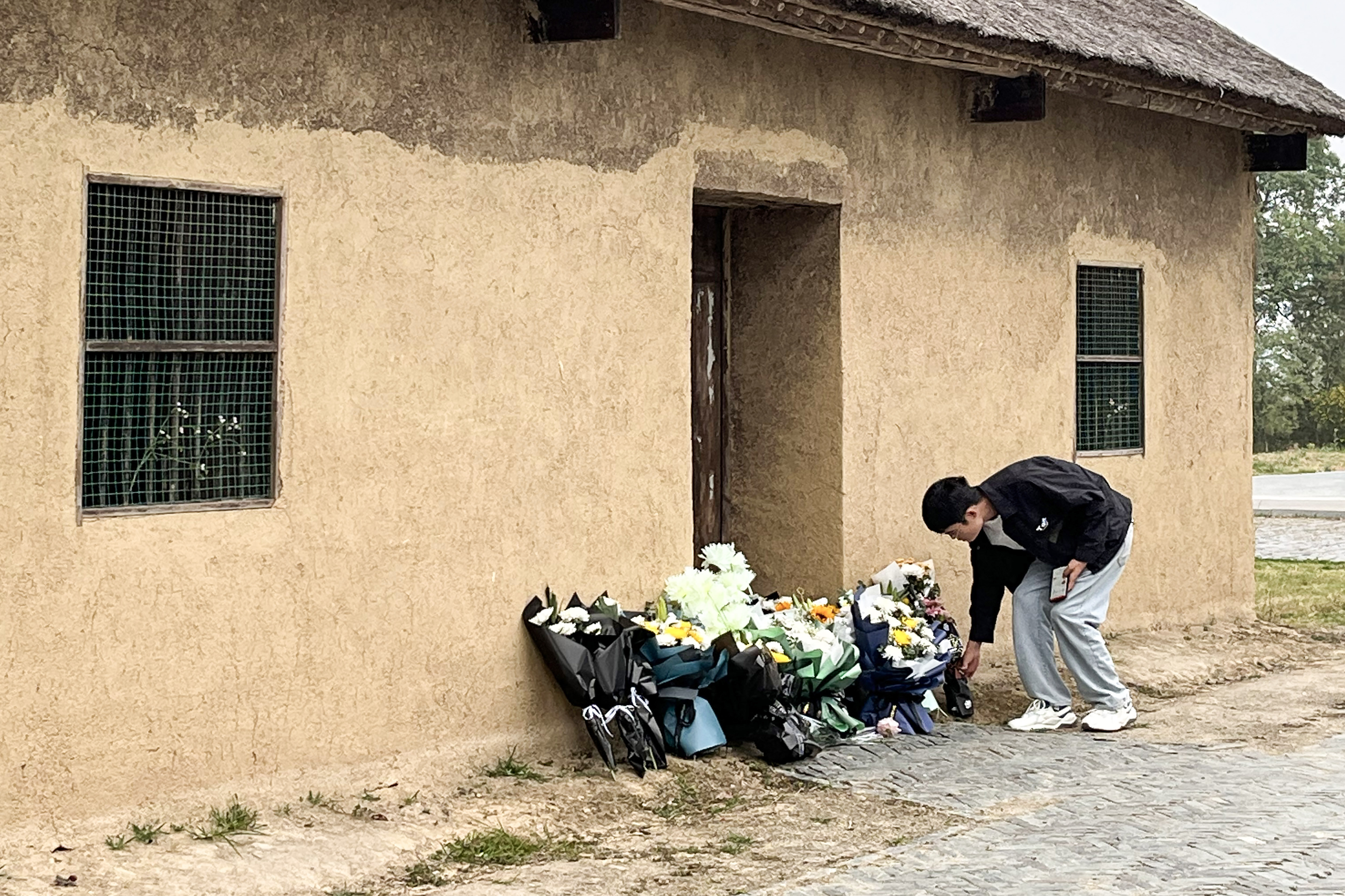A man leaves flowers in front of a former home of Li Keqiang. A few bouquets have already been left outside the door.