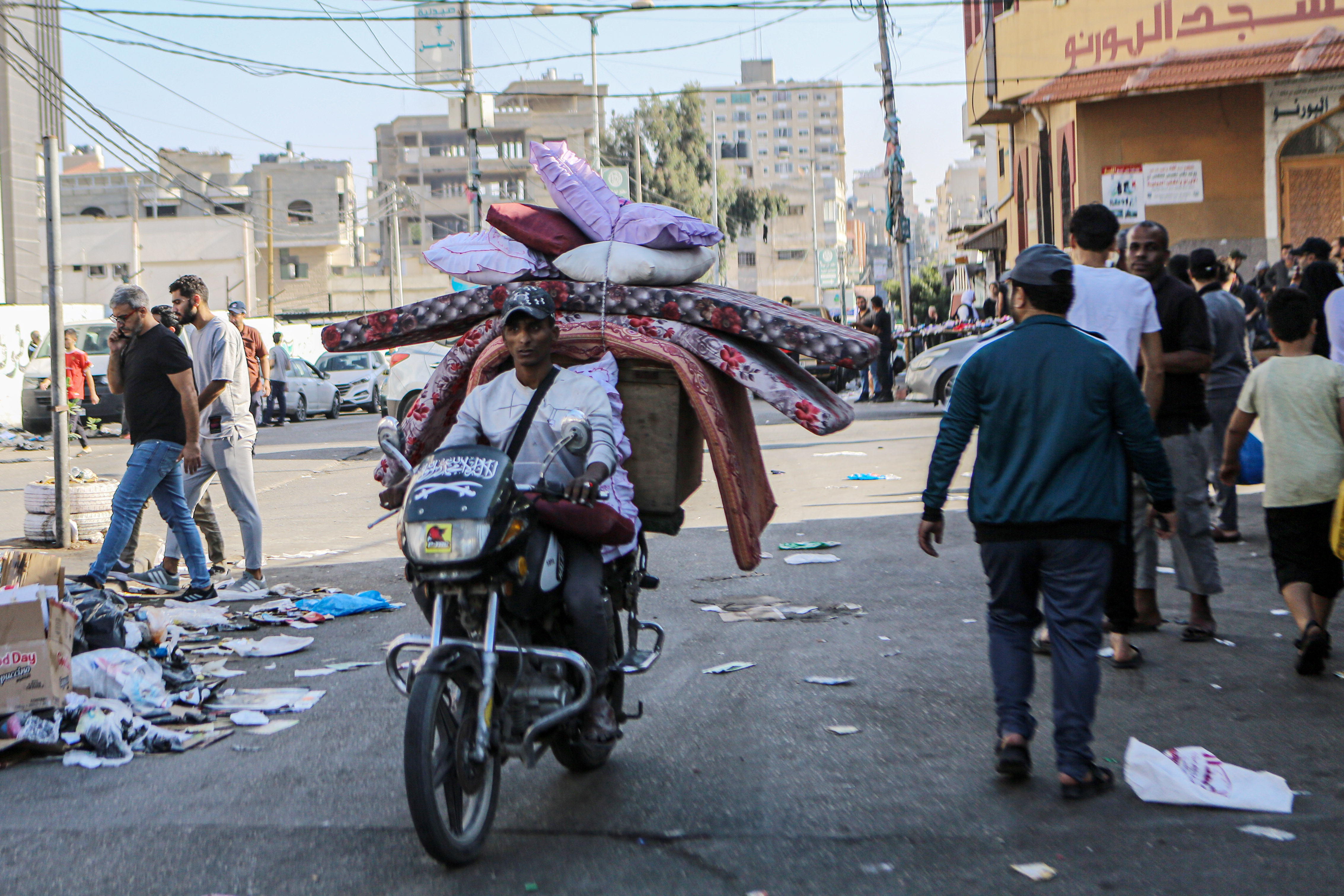 A man carries mattresses on a motorcycle