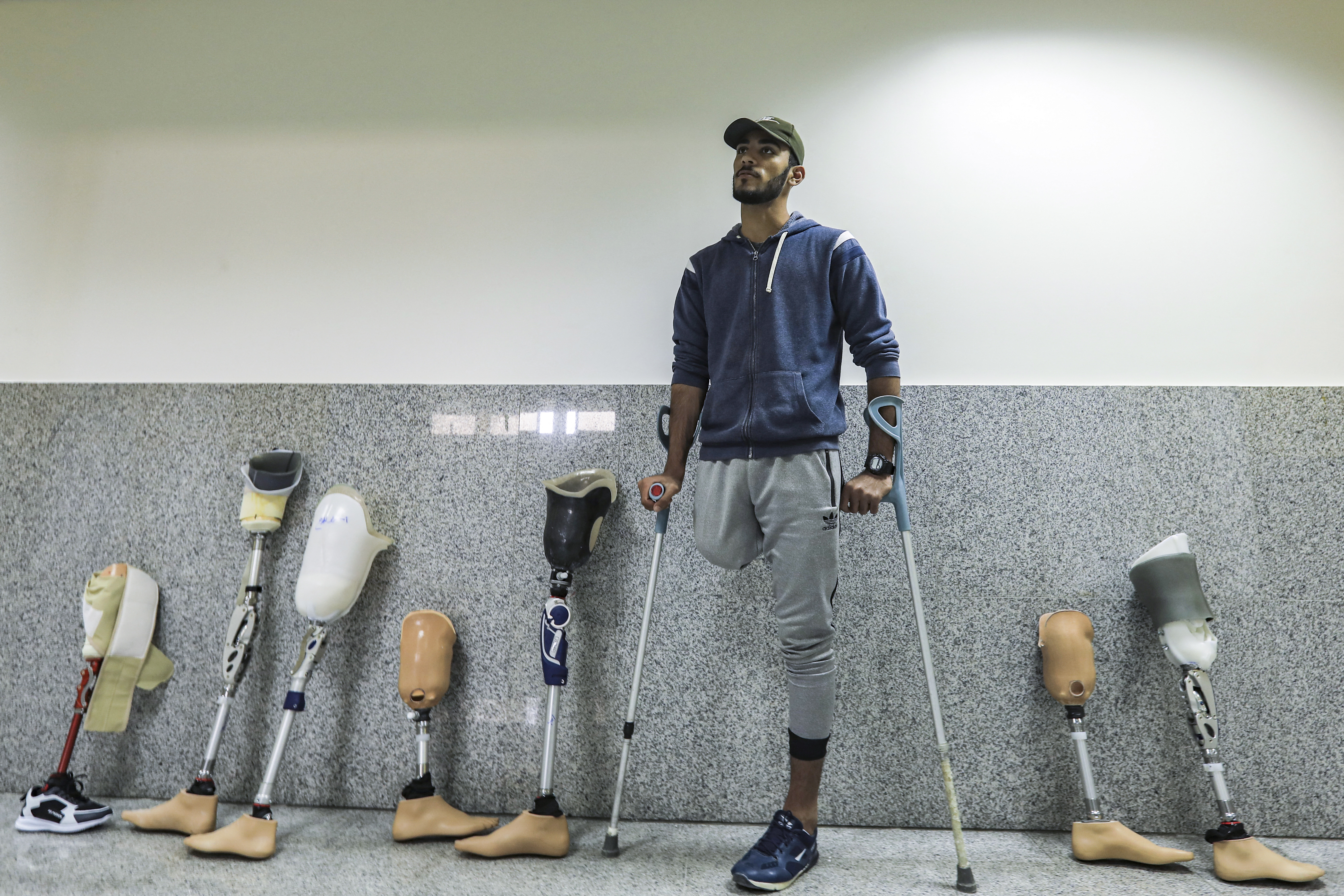 A Palestinian amputee leans on crutches next to prosthetic limbs lined up along a wall while waiting for treatment at the Qatar-funded Sheikh Hamad Bin Khalifa Al-Thani rehabilitation centre in Gaza City