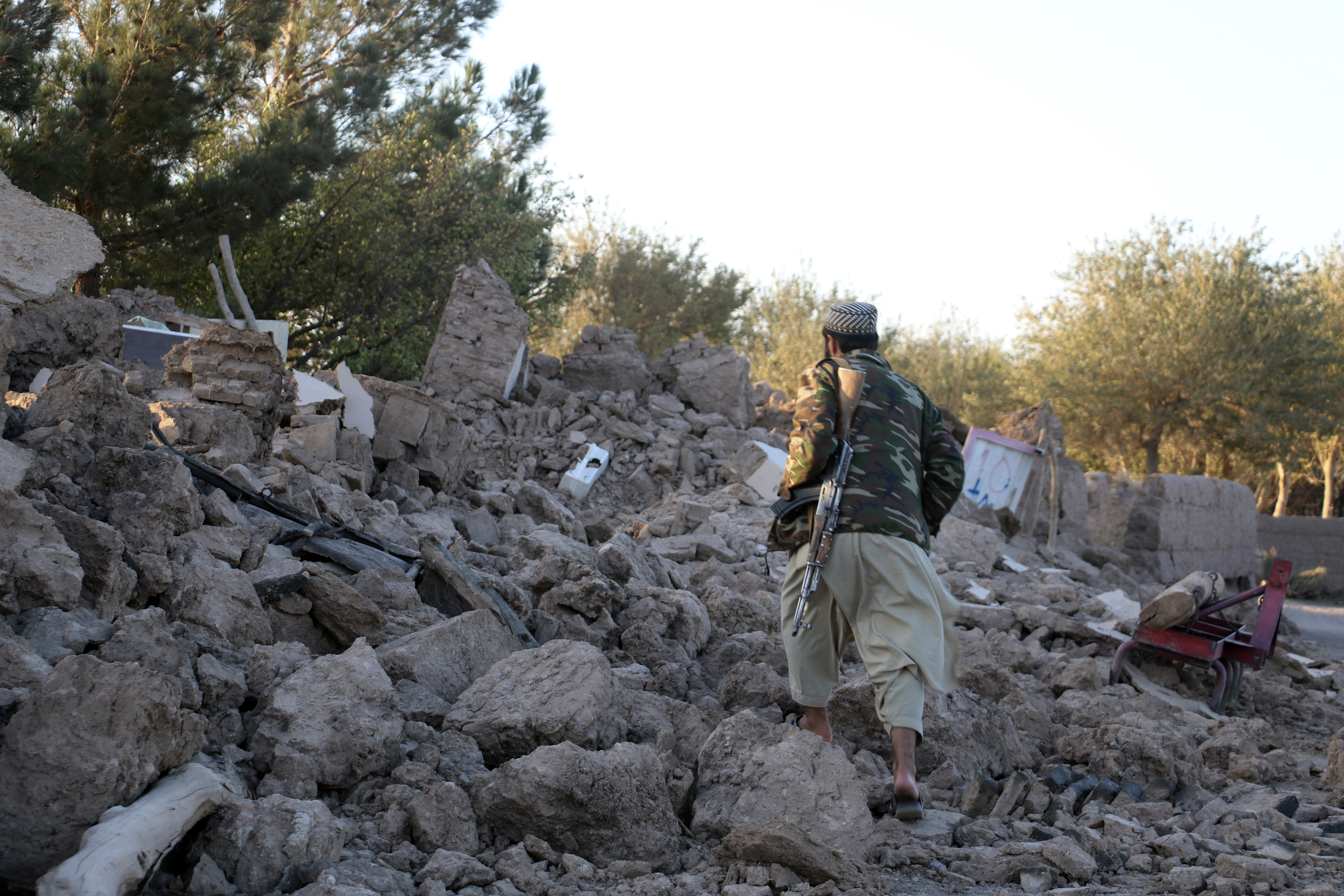 An Afghan man walks by a destroyed home after an earthquake in Zenda Jan district in Herat province, of western Afghanistan