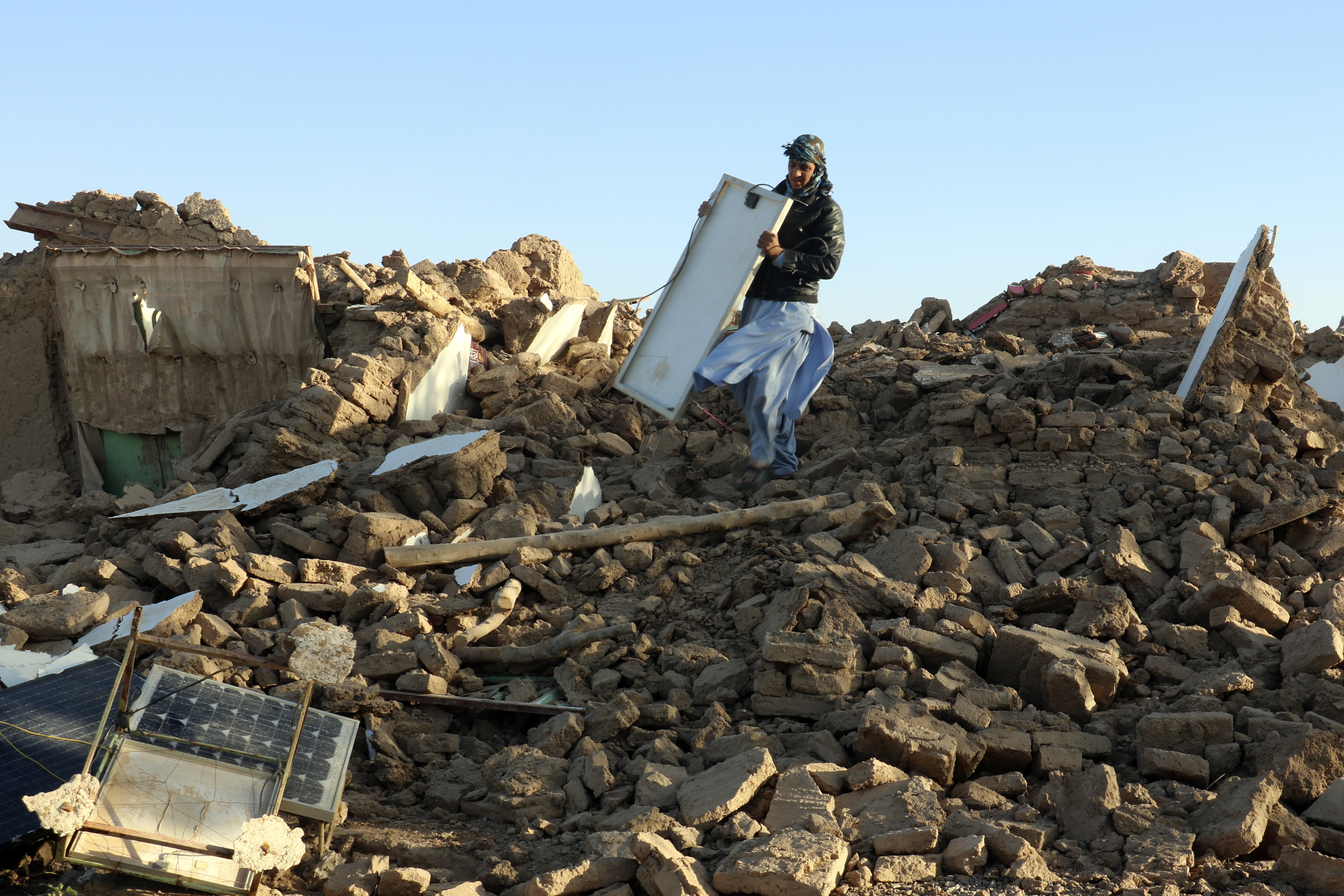 An Afghan man removes debris after an earthquake in Zenda Jan district in Herat province, of western Afghanistan