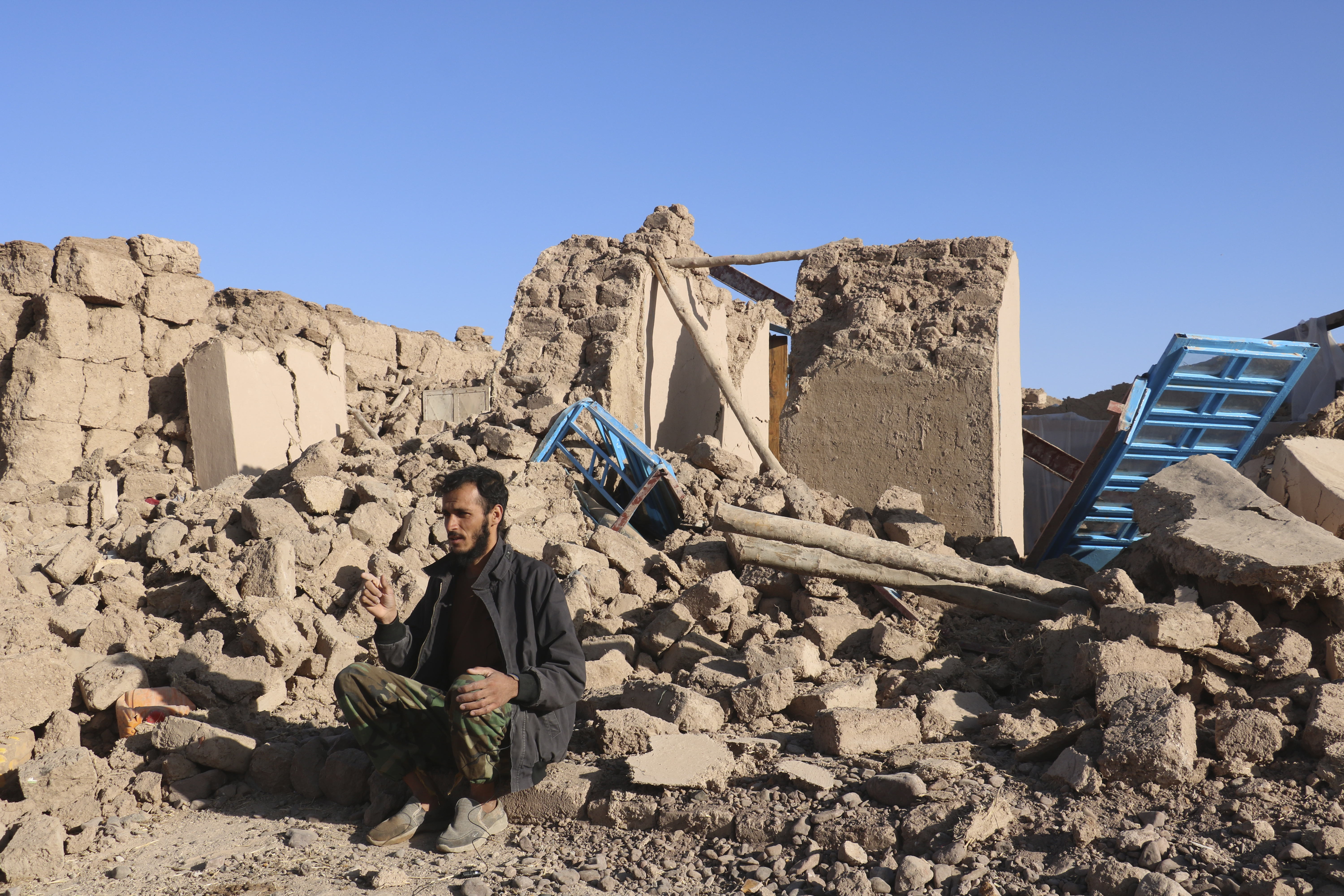 An Afghan man sits in a courtyard of a destroyed home after an earthquake in Zenda Jan district in Herat province