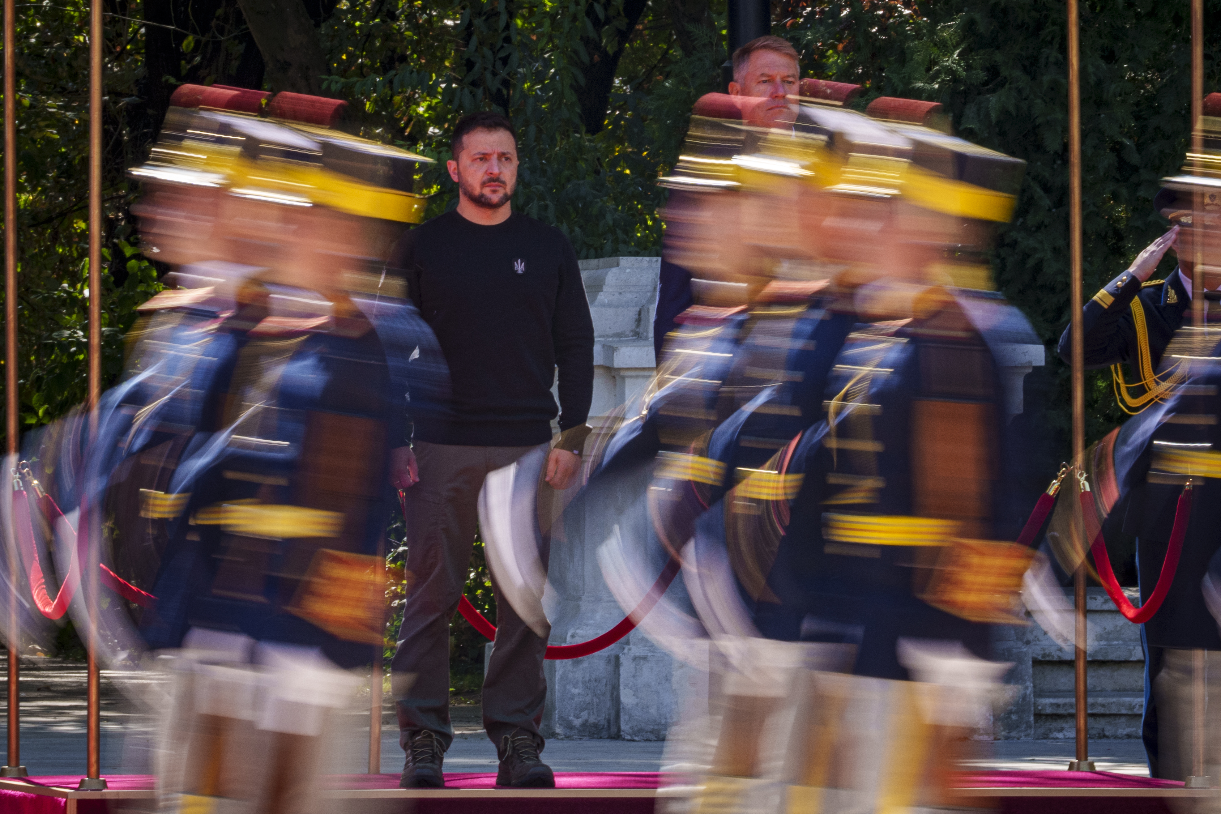 Volodymyr Zelenskyy seen through marching honour guards in Romania.