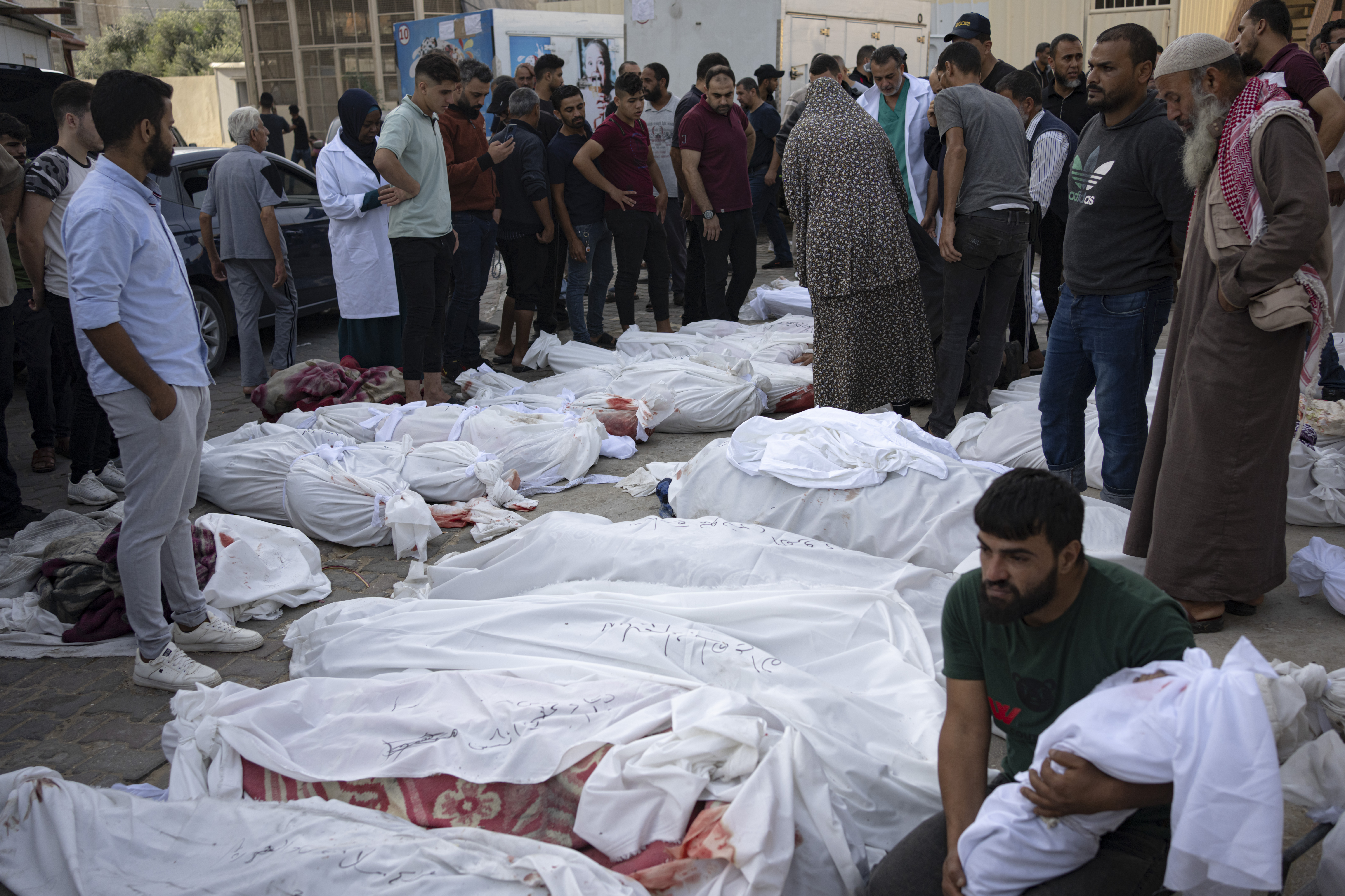Friends and relatives stand by the bodies of Palestinians killed in the Israeli bombardment of the Gaza Strip at Al-Aqsa Hospital in Deir Al-Balah