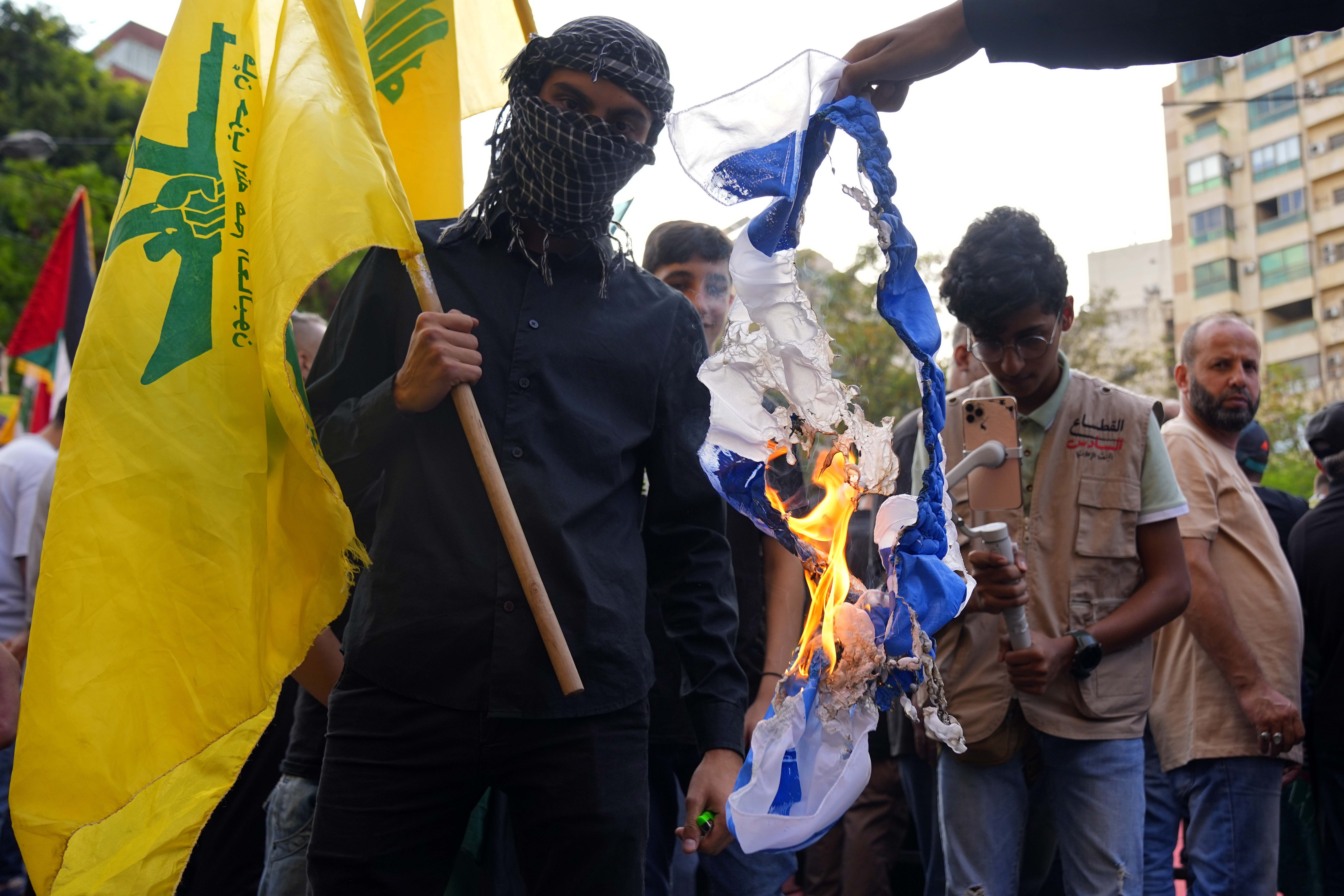 Hezbollah supporters burn an Israeli flag during a protest in solidarity with the Palestinian people in Gaza, in Beirut, Lebanon, Friday, Oct. 27, 2023. (AP Photo/Bilal Hussein)