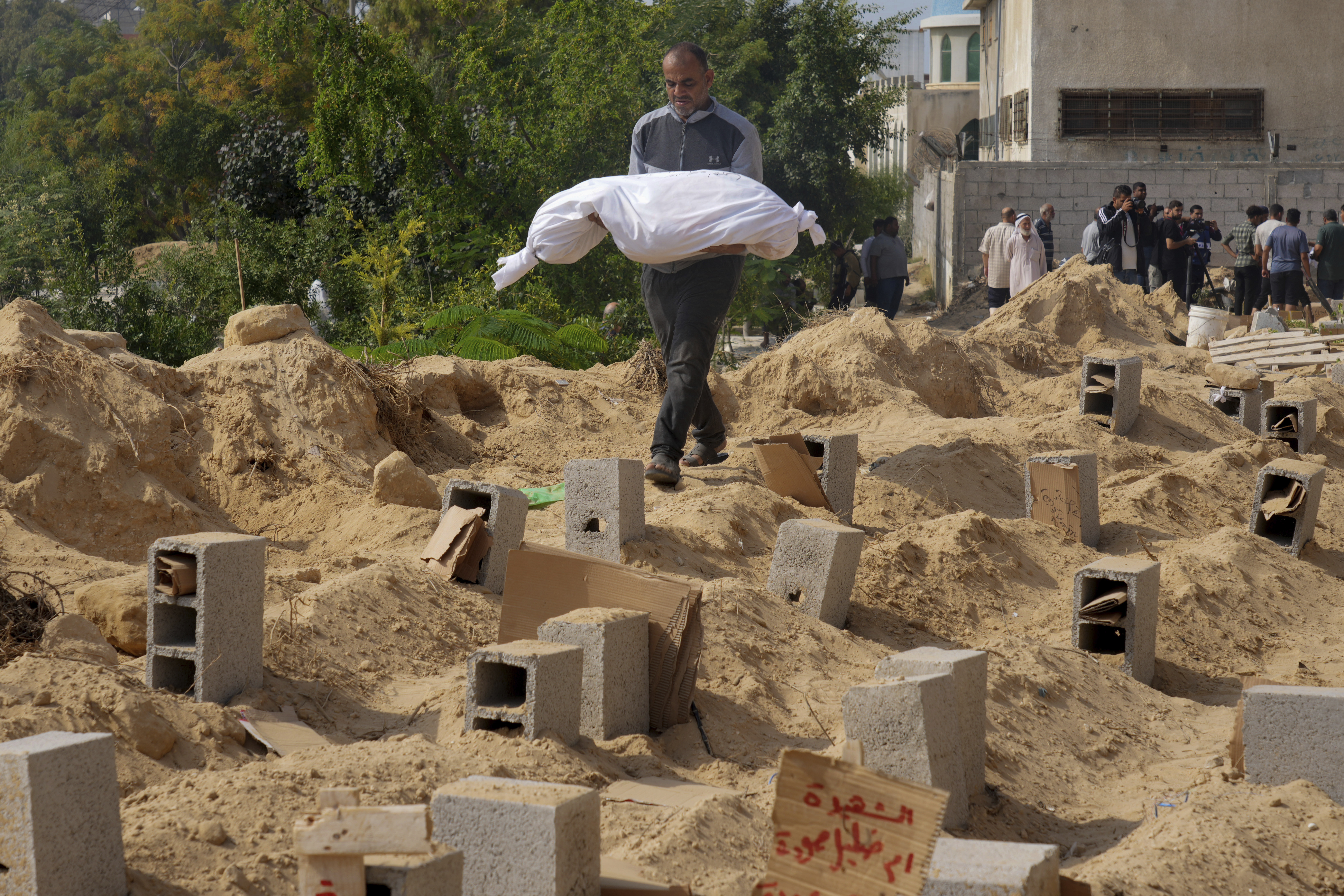Palestinians bury the bodies of their relatives killed in the Israeli bombardment of the Gaza Strip, at a cemetery in Deir Al-Balah