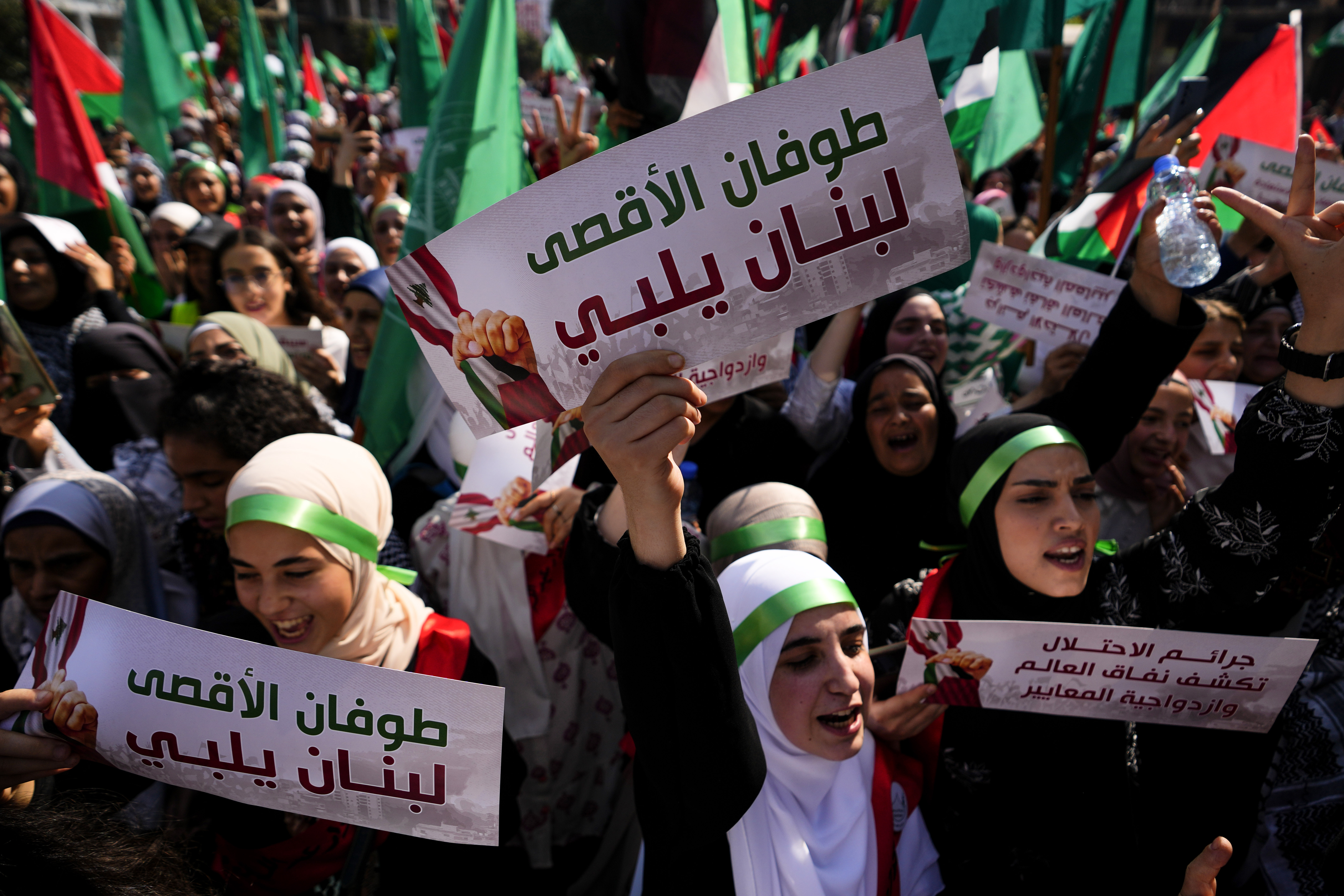 A crowd of people wave signs and carry Palestinian flags in Beirut.
