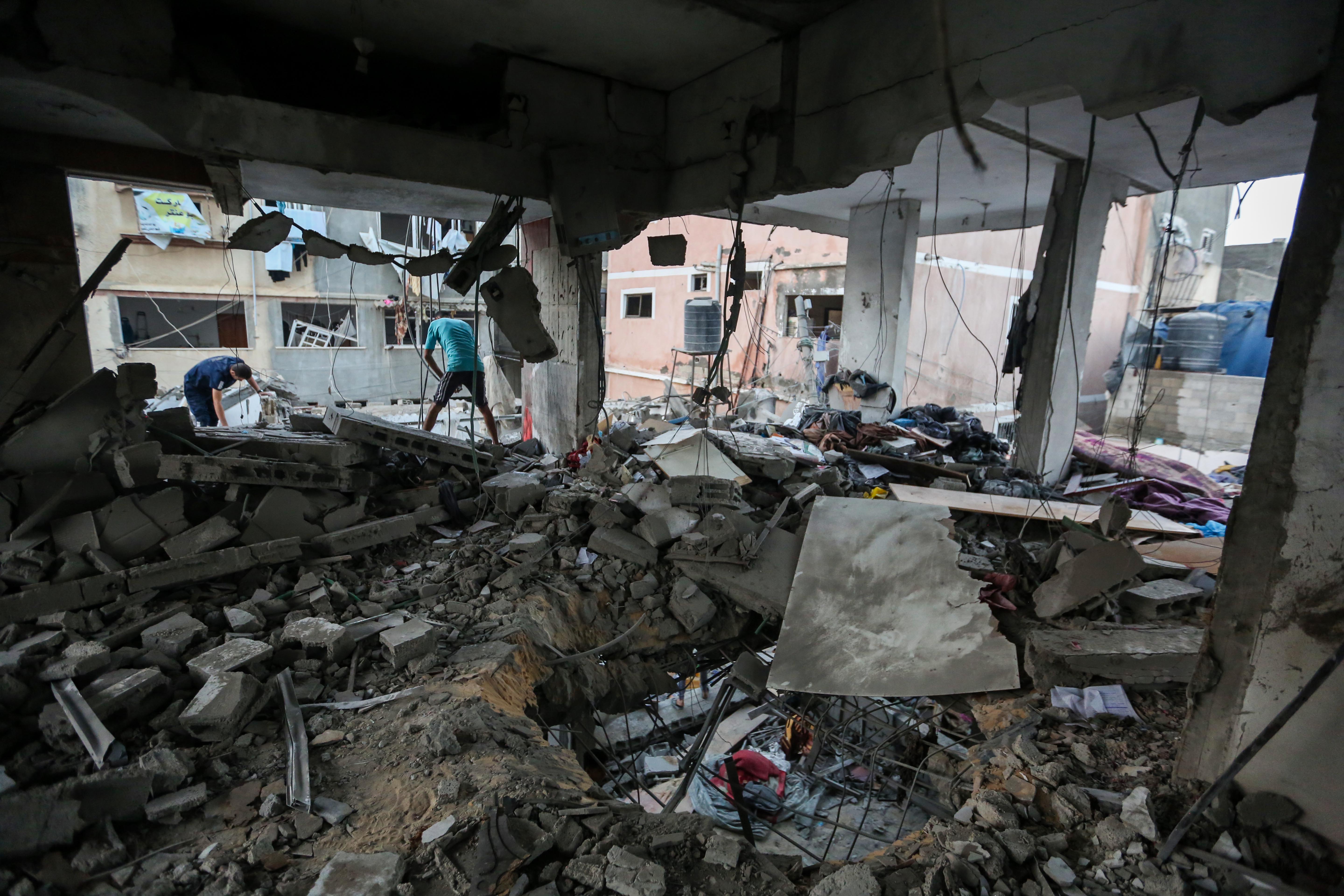 People search for survivors and the bodies of victims through buildings that were destroyed during Israeli bombardment, in Khan Yunis