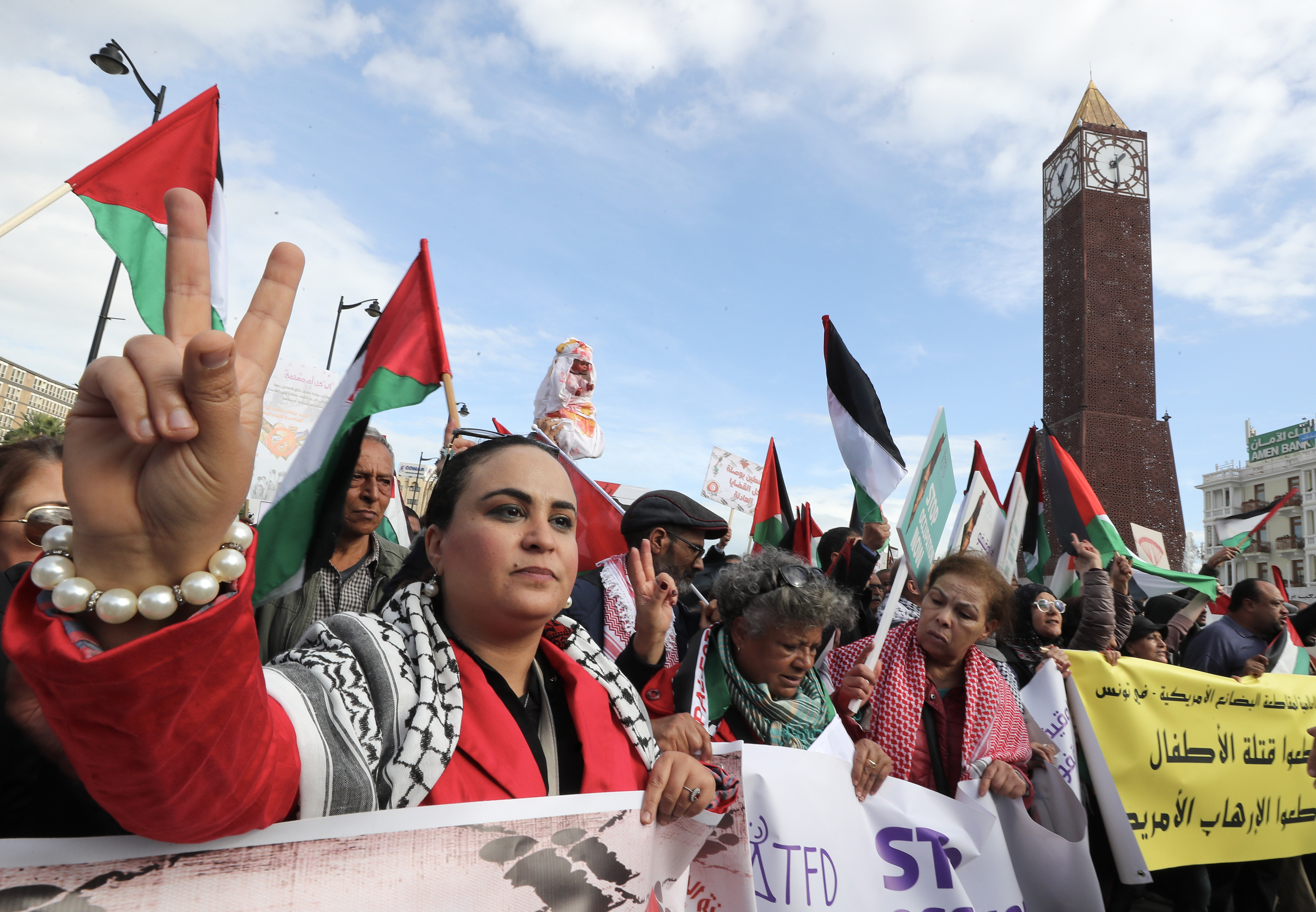 A Tunisian activist gestures while displaying a banner during a protest in solidarity with the Palestinian people, to mark the International Day of Solidarity with the Palestinian People, in Tunis, Tunisia.