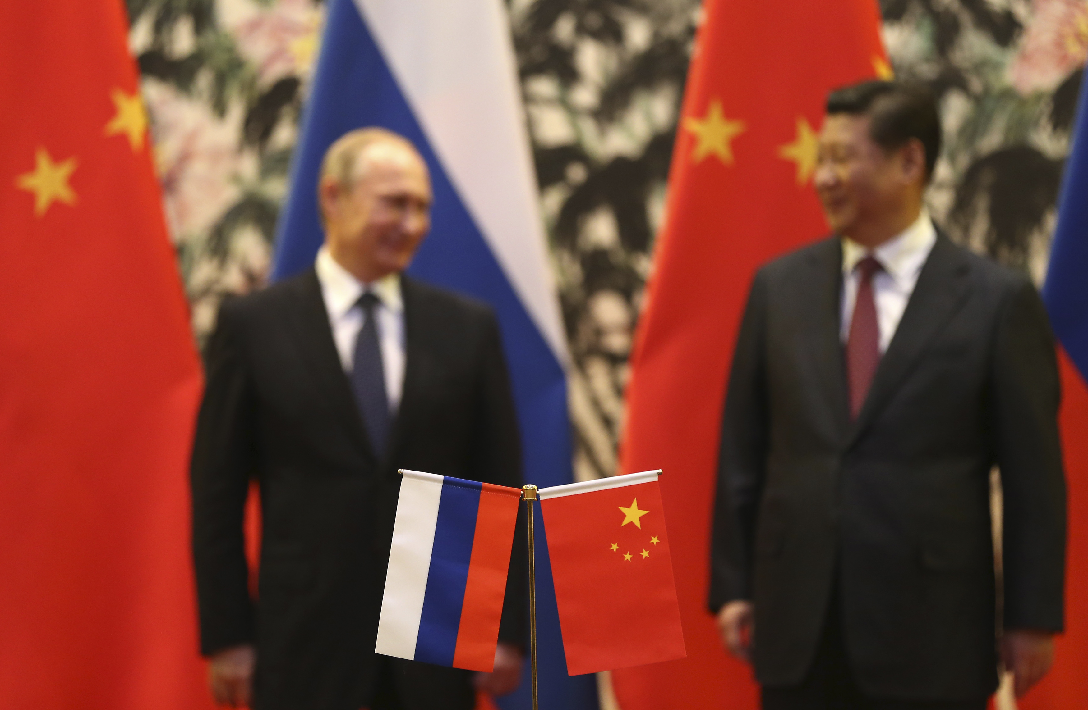 flags of China and Russia surrounding the countries' presidents