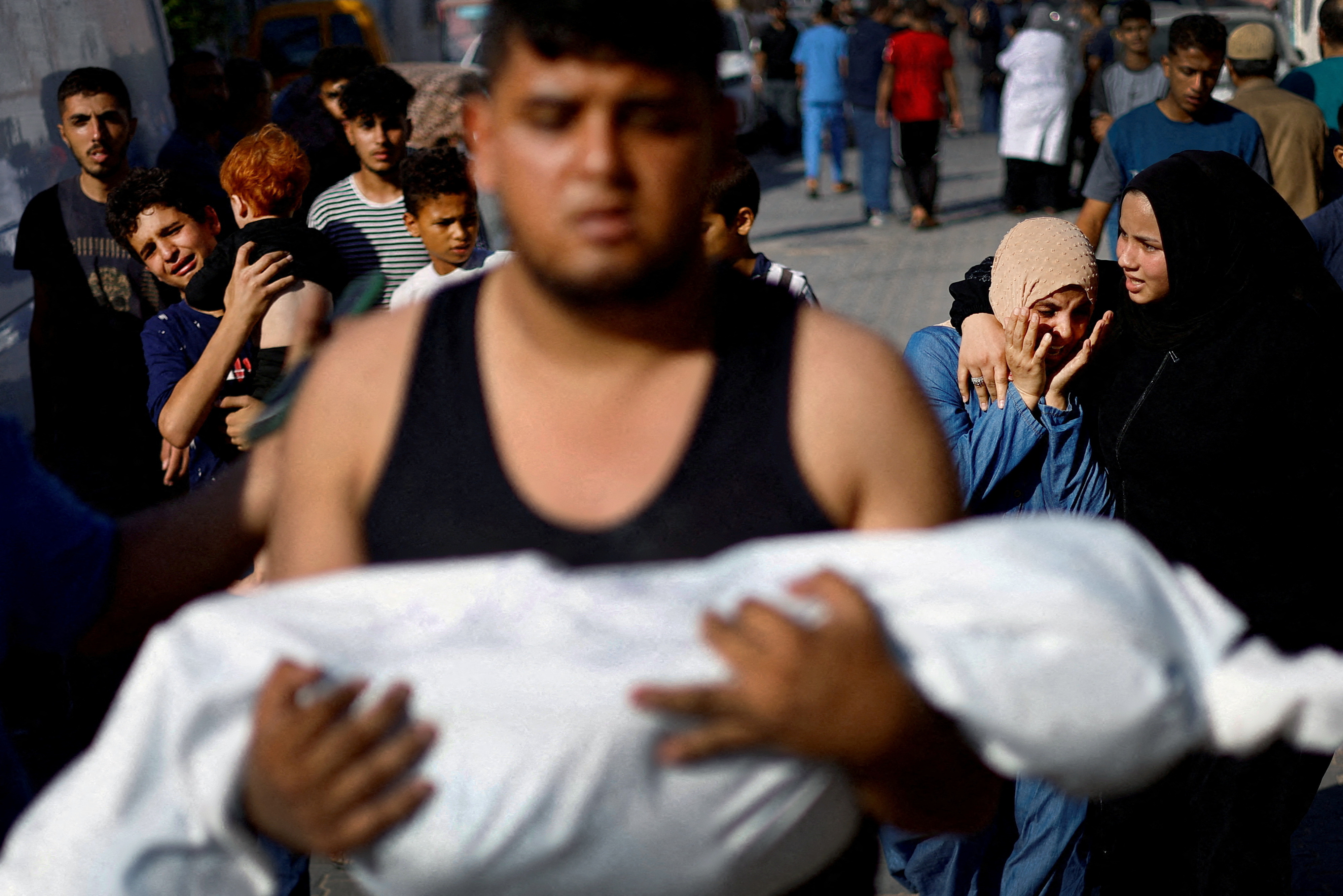A man carries the body of Palestinian girl Saly, 5, who was killed in an Israeli strike as her aunt Inas Abu Maamar, 36, reacts during her funeral in Khan Younis in the southern Gaza Strip.