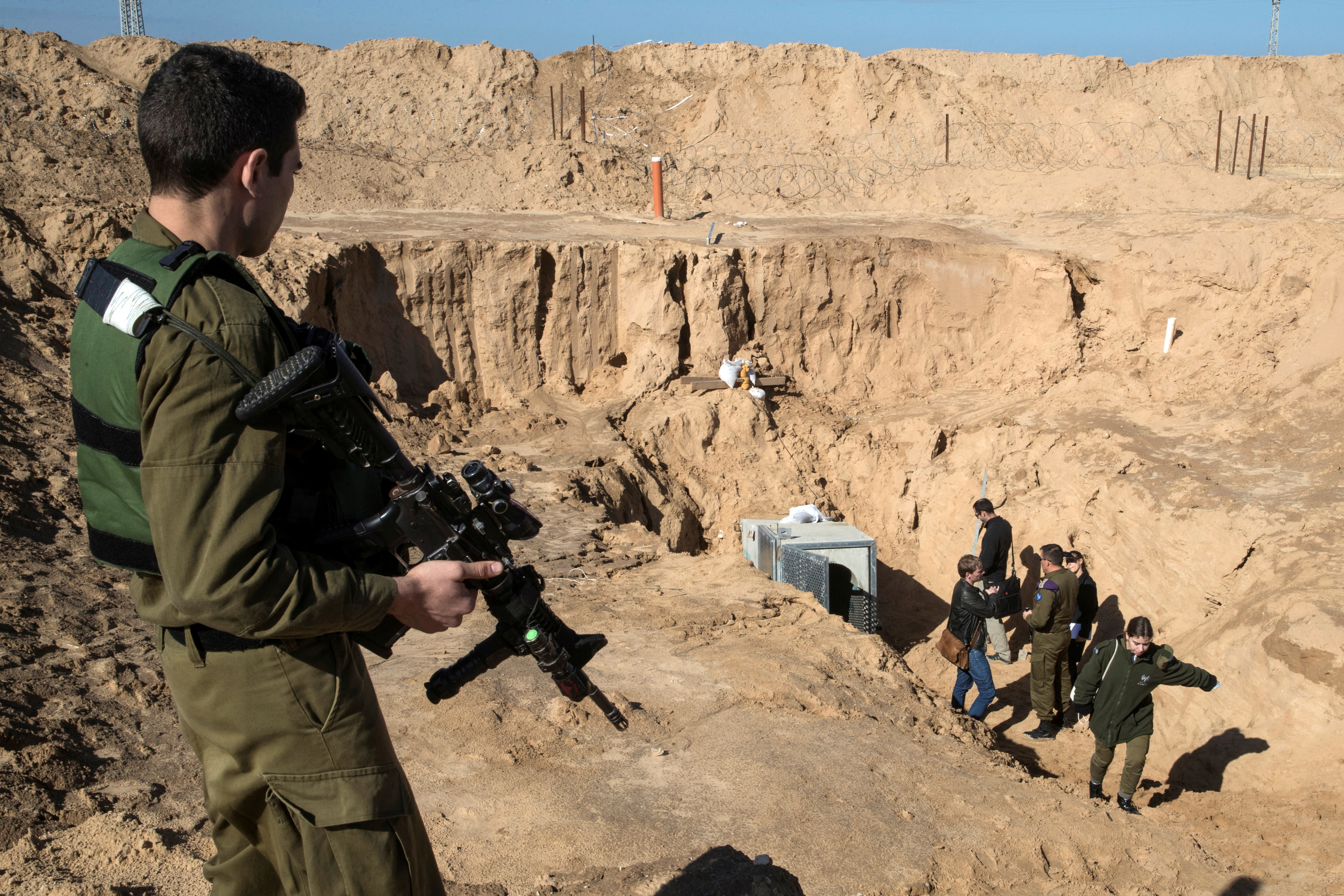 An Israeli soldier keeps guard next to an entrance to what the Israeli military say is a cross-border attack tunnel dug from Gaza to Israel, on the Israeli side of the Gaza Strip border near Kissufim