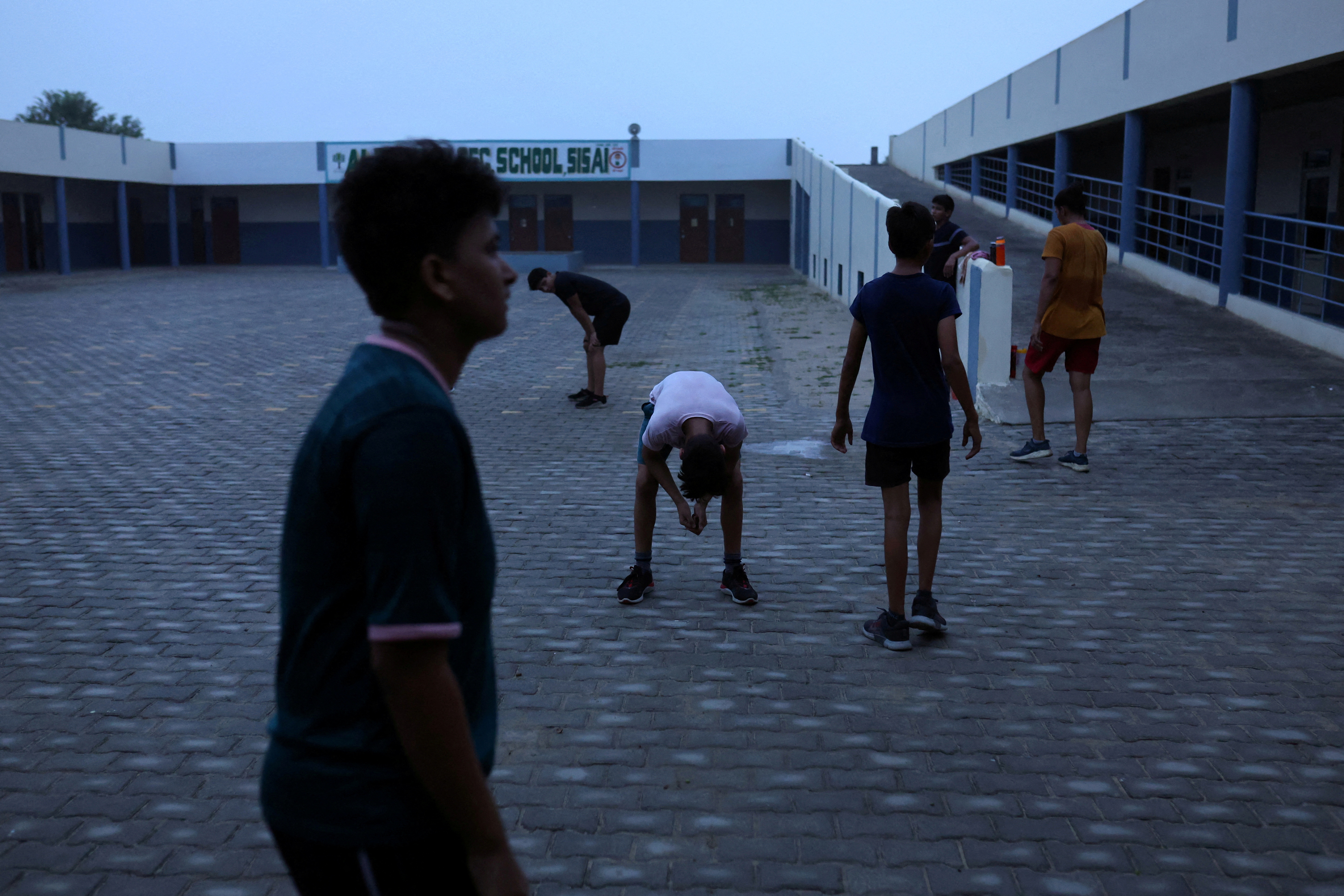 Students take a break in between the morning fitness and practice session on the playground at The Altius Wrestling School in Sisai, Haryana, India.