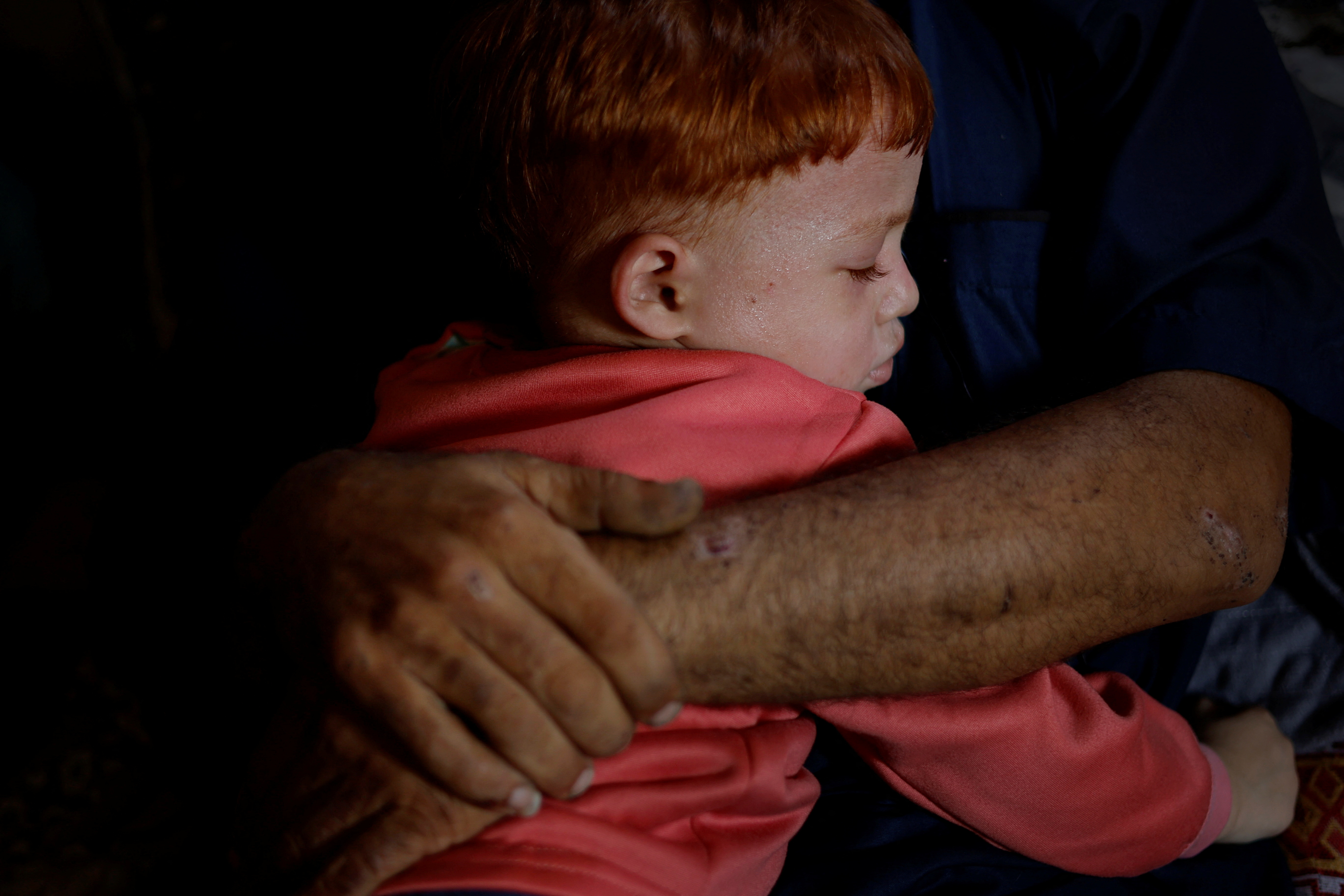 Ramez Abu Maamar, the father of Palestinian girl Saly, 5, who was killed in an Israeli air strike, holds his son Ahmed, 4, in Khan Younis in the southern Gaza Strip.