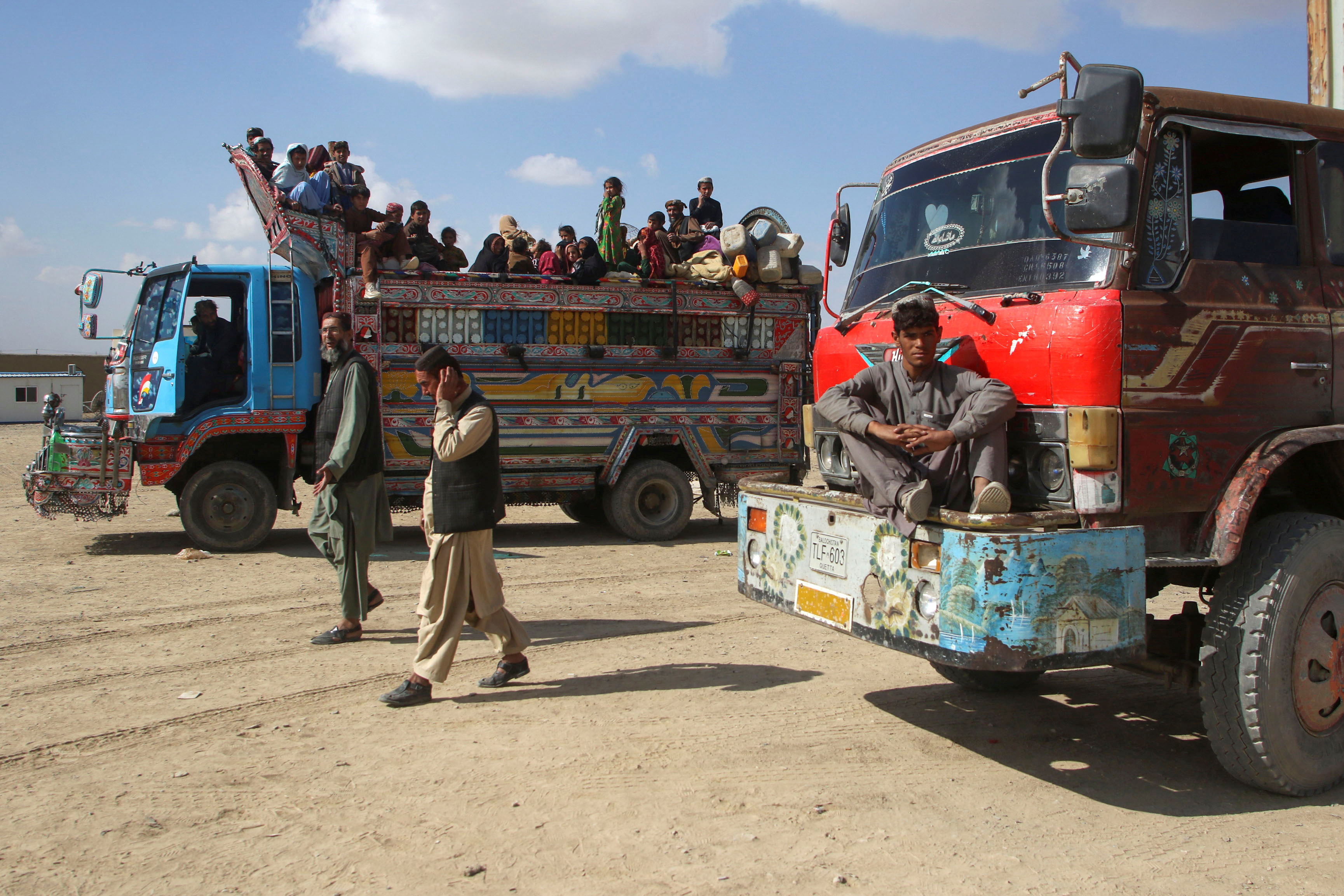 Afghan men walk as a family boards a truck as they head back to Afghanistan from Pakistan, at the Chaman Border Crossing along the Pakistan-Afghanistan Border in Balochistan Province, in Chaman, Pakistan November 9, 2023