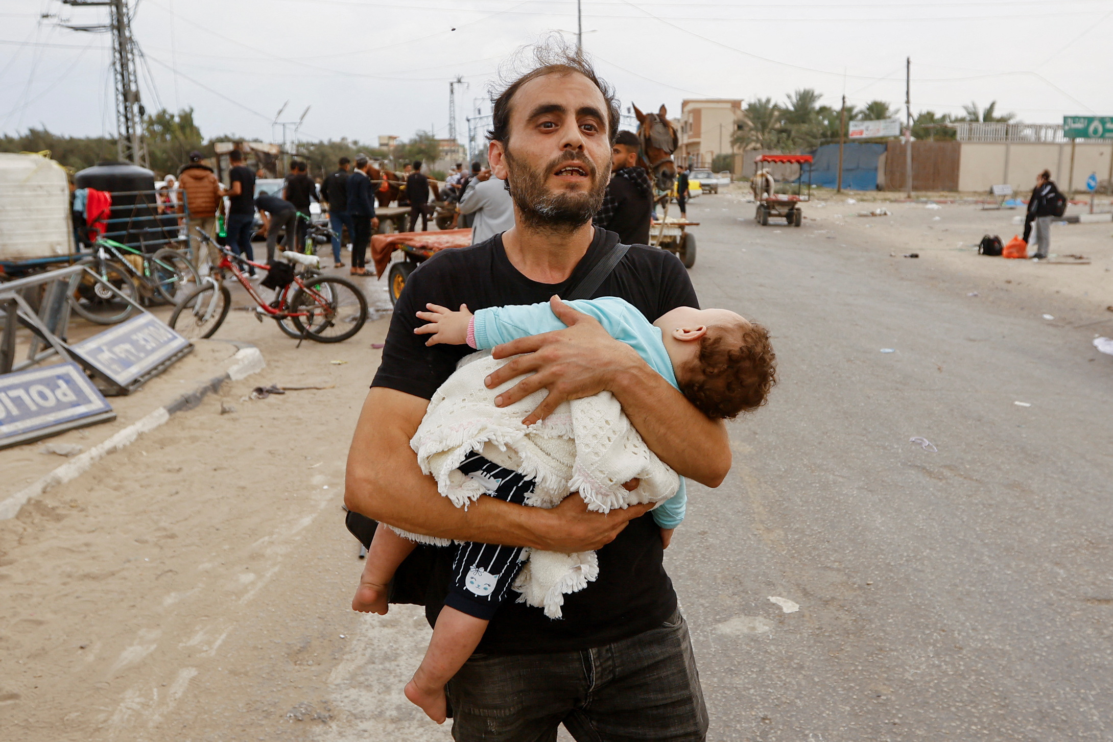 A Palestinian man holding a child flees north Gaza as they move southward, as Israeli tanks roll deeper into the enclave, amid the ongoing conflict between Israel and Hamas, in the central Gaza Strip November 12, 2023. REUTERS/Ibraheem Abu Mustafa