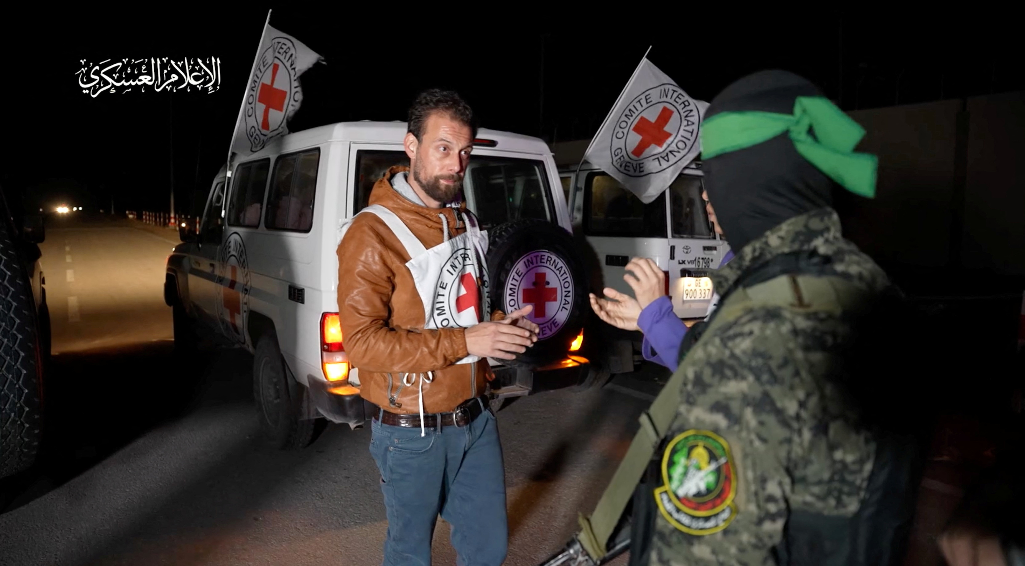 A Hamas militant interacts with members of the International Committee of the Red Cross, as Hamas militants hand over hostages who were abducted during the October 7 attack on Israel to members of the International Committee of the Red Cross, as part of a hostages-prisoners swap deal between Hamas and Israel amid a temporary truce, in an unknown location in the Gaza Strip, in this screengrab taken from video released November 27, 2023. Hamas Military Wing/Handout via REUTERS THIS IMAGE HAS BEEN SUPPLIED BY A THIRD PARTY. WATERMARK FROM SOURCE.