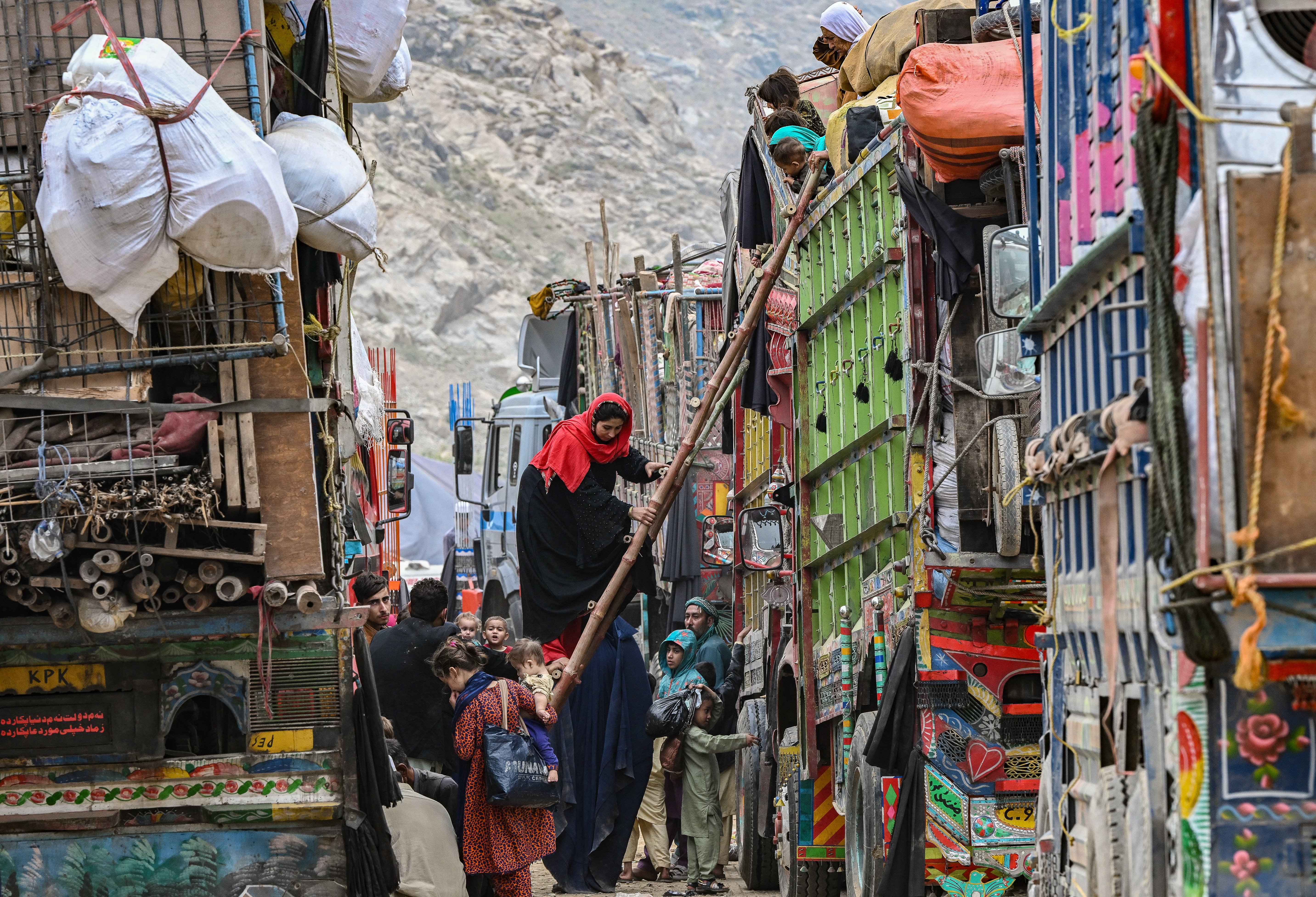 Afghan refugees climb a truck as they prepare to depart for Afghanistan, at a holding centre in Landi Kotal.