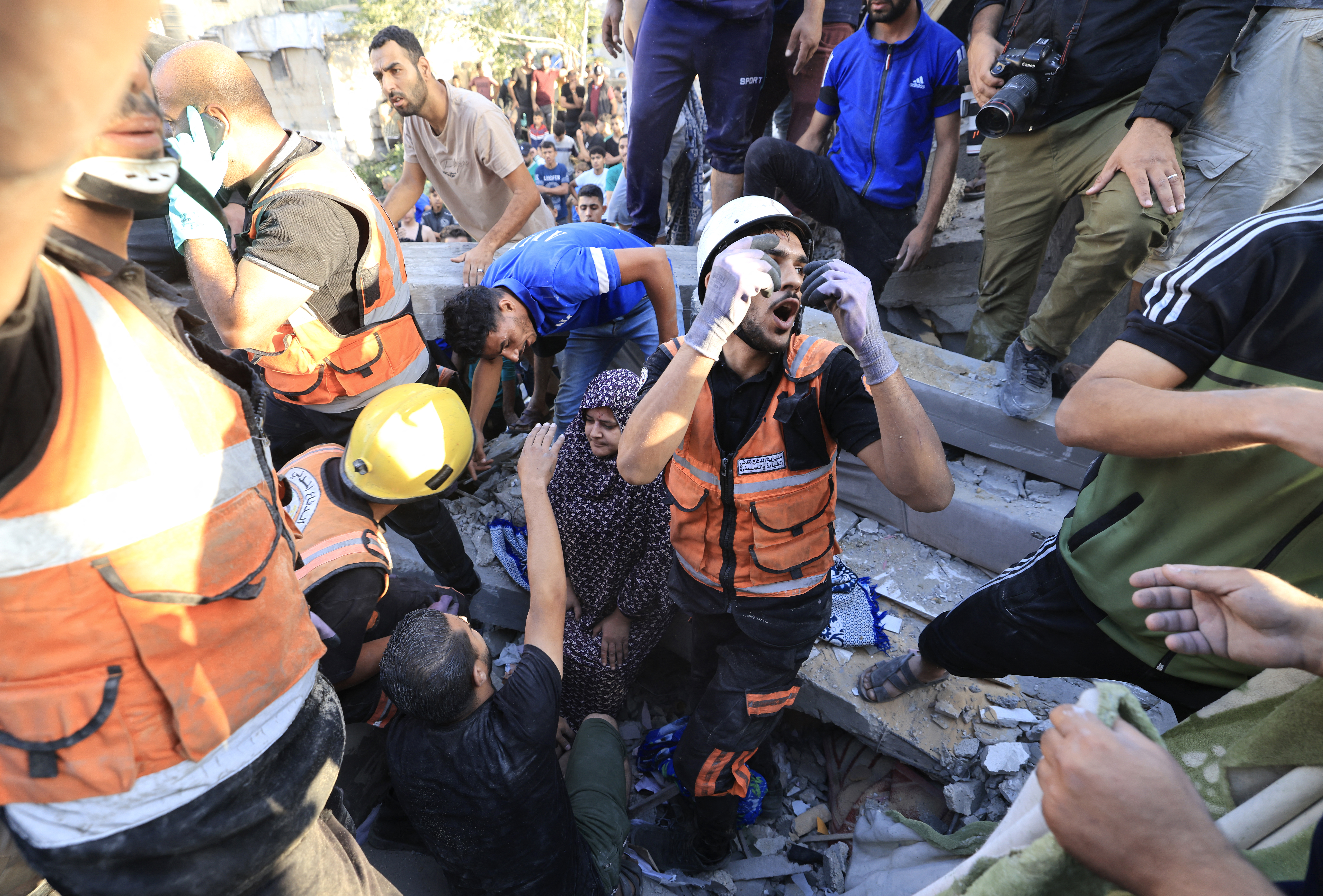 A Palestinian woman sits on the rubbles as rescuers look for her relatives following the Israeli bombardment of Khan Yunis