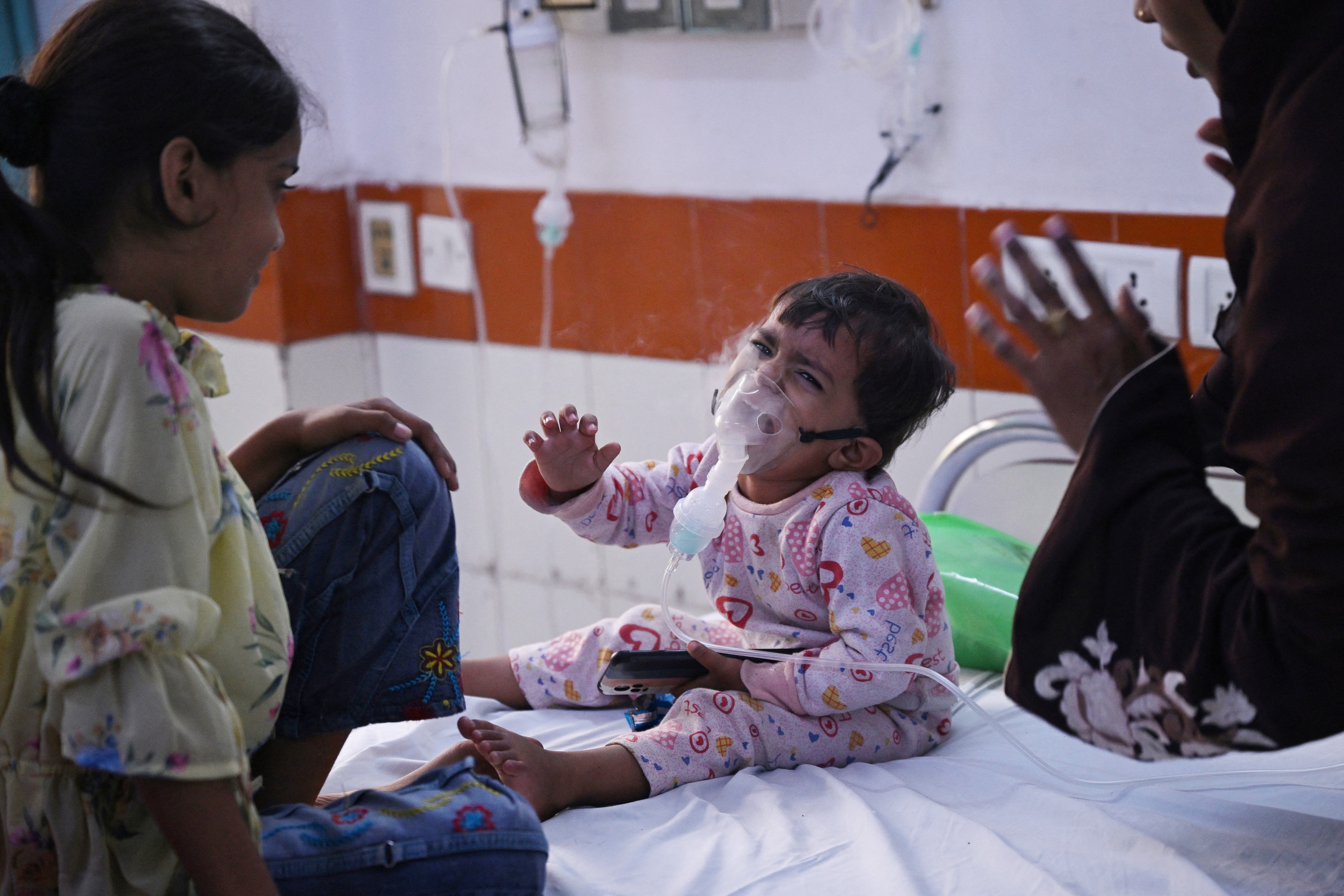 In this picture taken on November 7, 2023, a child reacts as he breathes with the help of a nebuliser at the emergency ward of the government-run Chacha Nehru Bal Chikitsalaya children hospital in New Delhi.